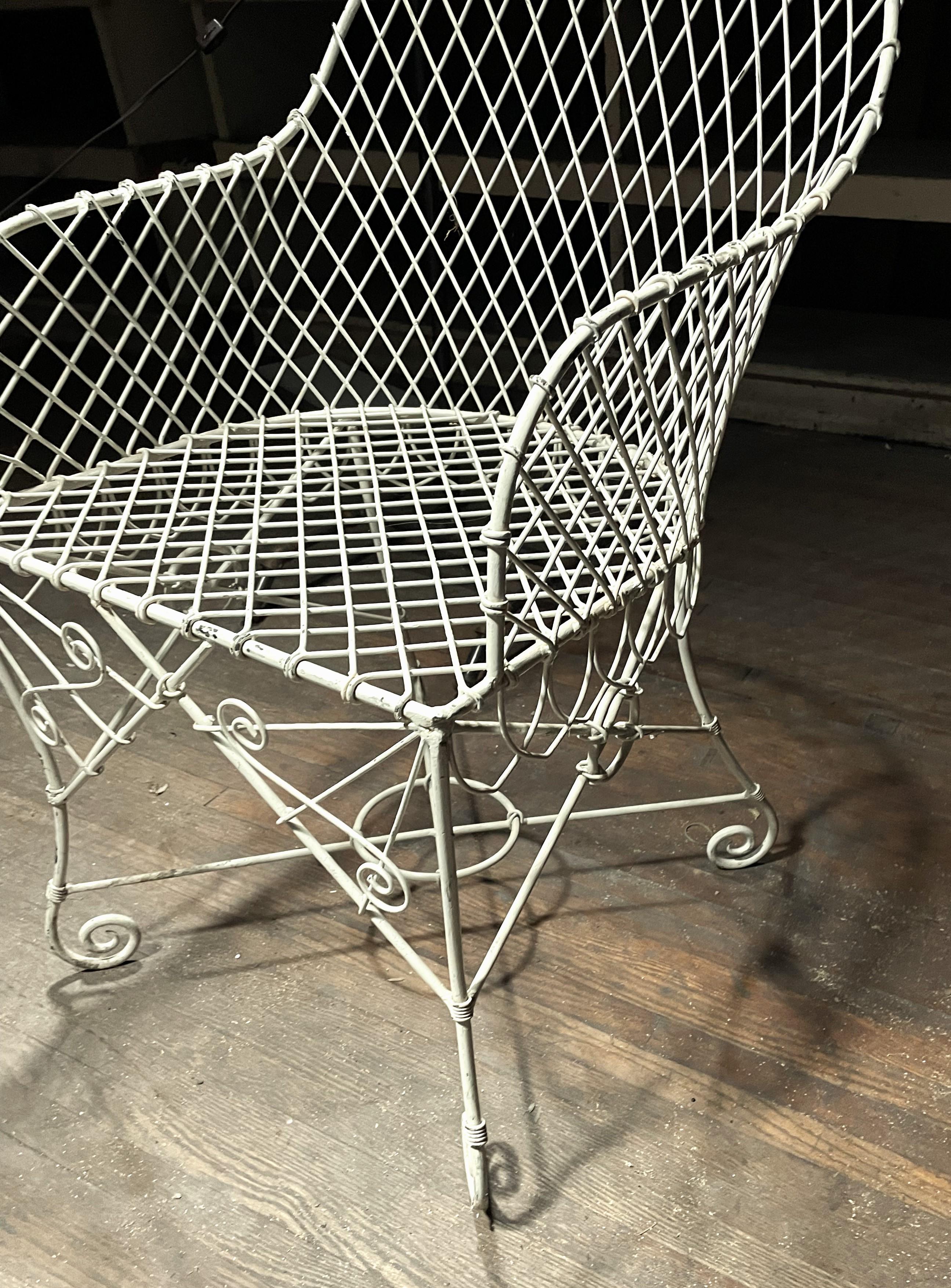 This is the sweetest French wire tub back chair with a wonderful aged paint finish, fantastic lines and scroll feet. The iron work is extremely well done but there is some paint loss especially on the arms and one leg seems to have gotten bent