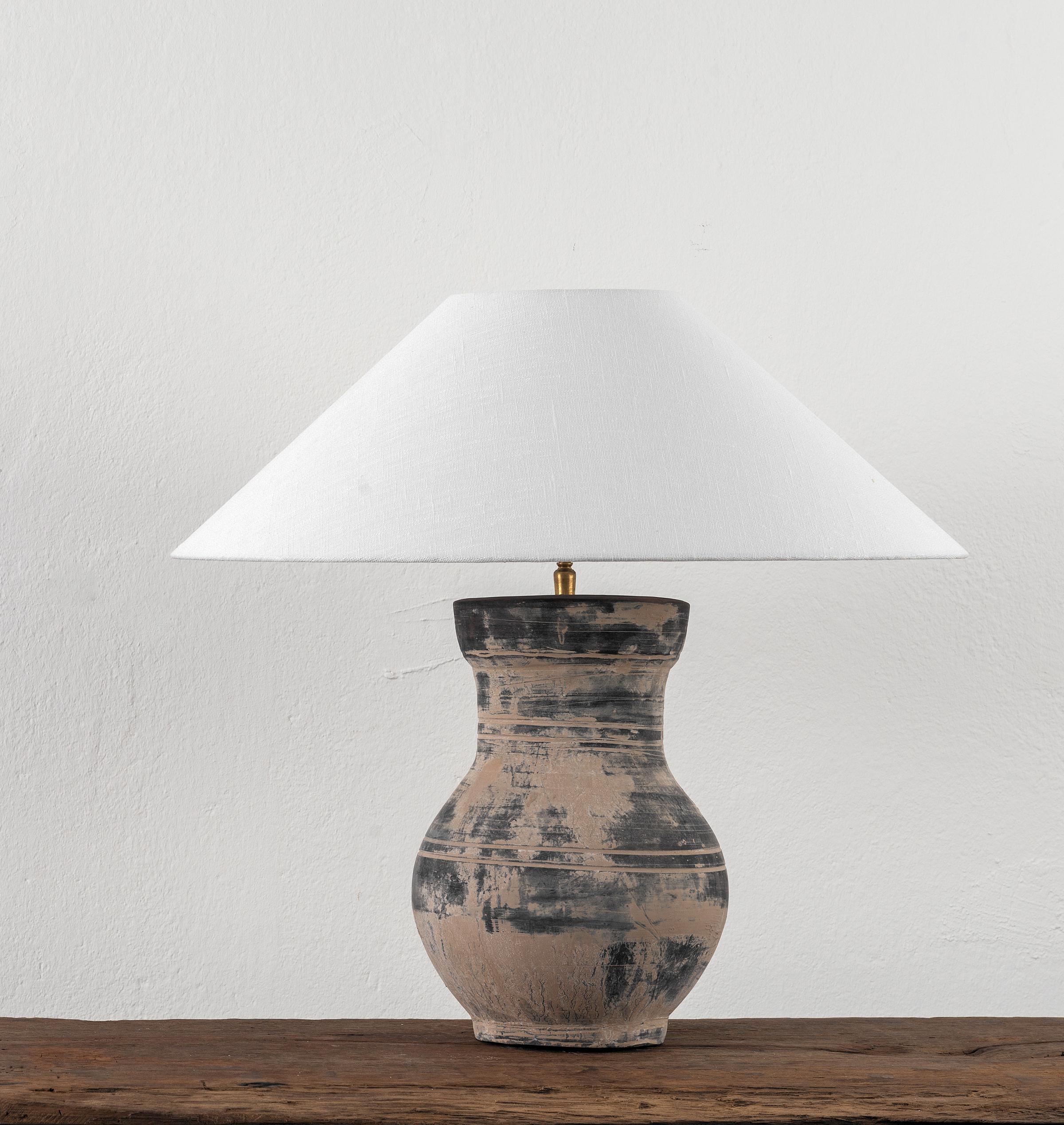 A beautiful unglazed Han dynasty style vase of a very elegant form.
Expectedly mounted as lamp - US WIRED. High quality mount with a brass adjustable pivot joint. 
The vase is from Zhejiang, china, mount and shade are made in Antwerp.
The Lamp is