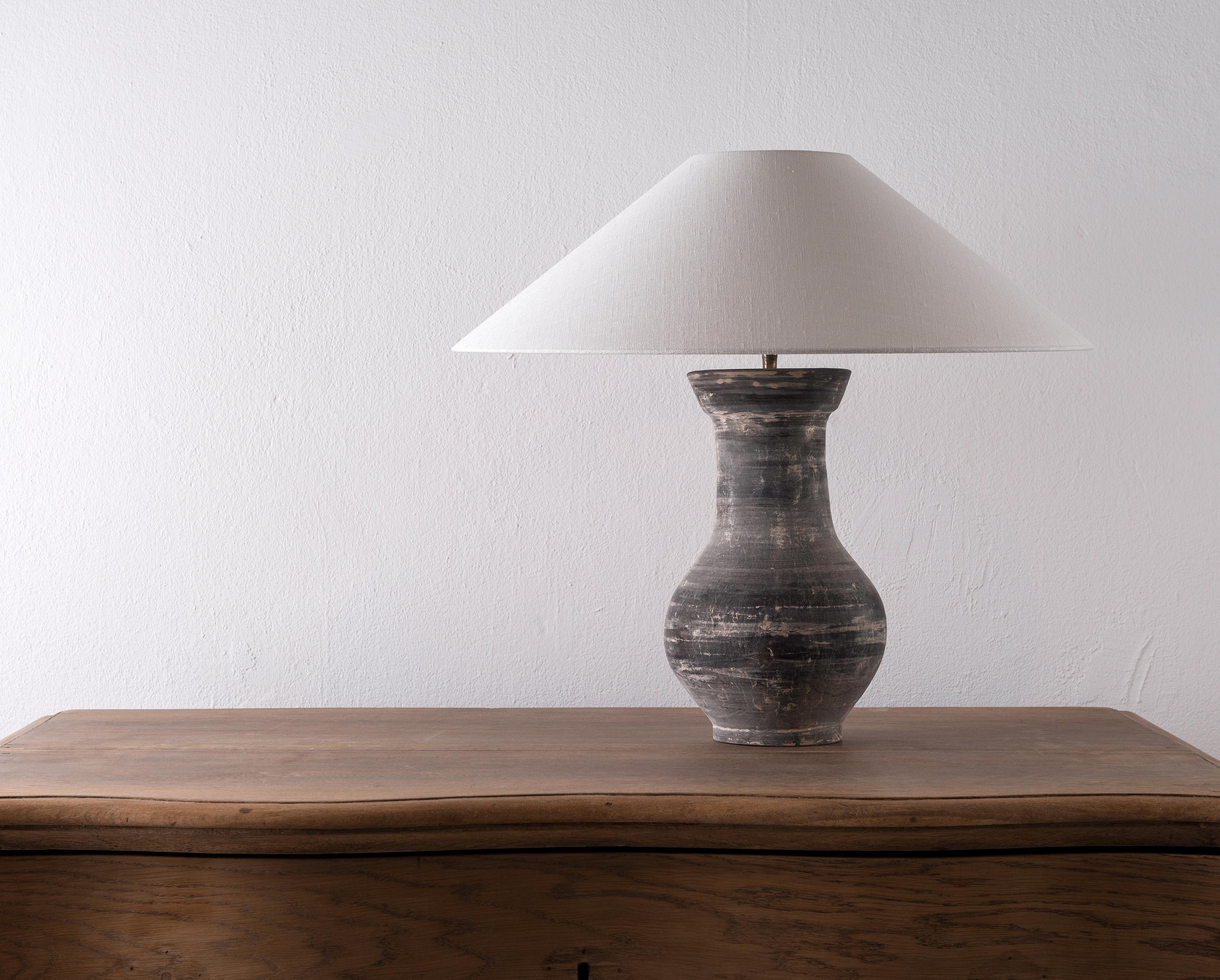 A beautiful unglazed Han dynasty style vase of a very elegant form.
Expectedly mounted as lamp. High quality mount with a brass adjustable pivot joint. Shade handmade in Belgium.
The vase is from Zhejiang, china, mount and shade are made in Antwerp.