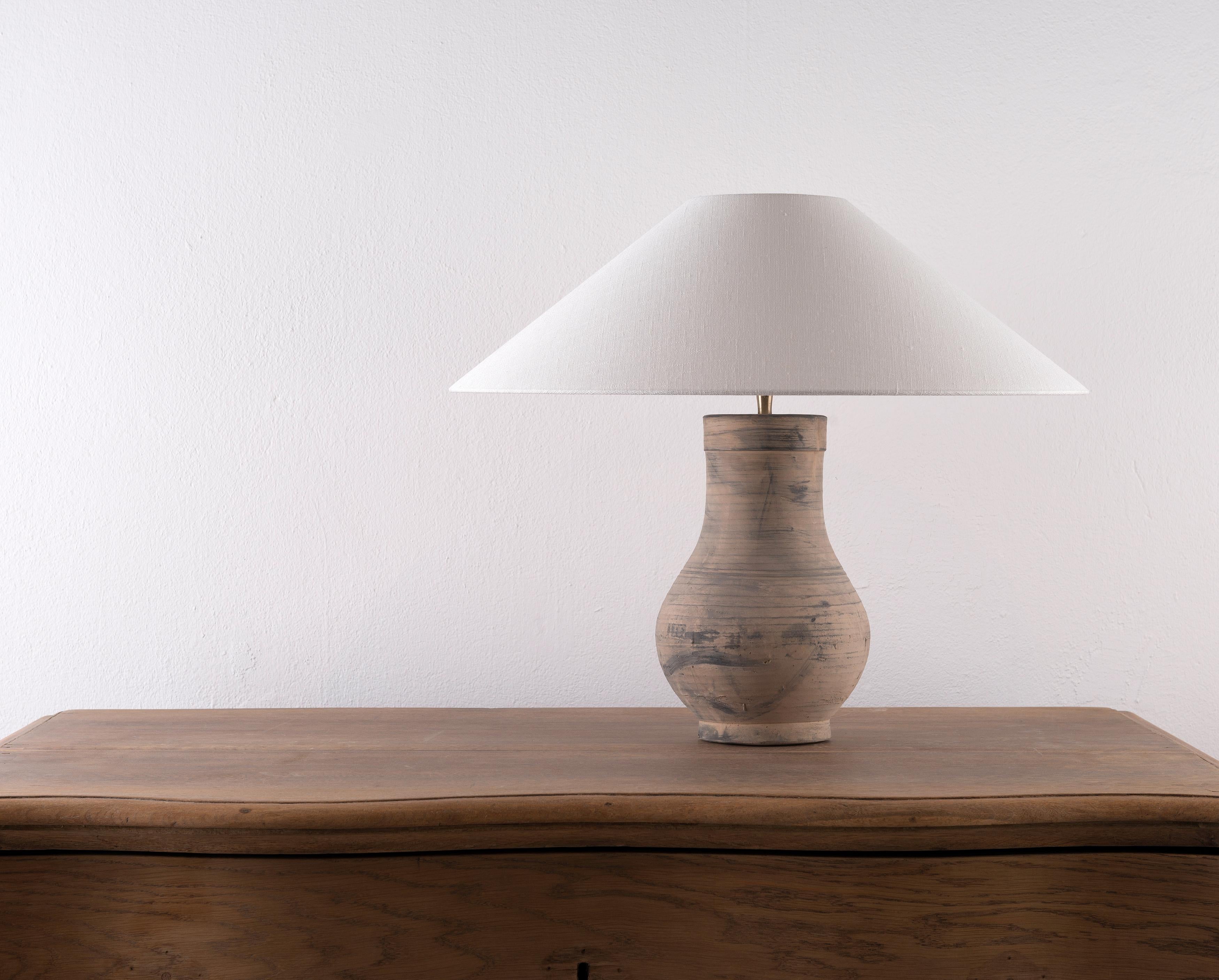 A beautiful unglazed Han dynasty style vase of a very elegant form.
Expectedly mounted as lamp. High quality mount with a brass adjustable pivot joint. Shade handmade in Belgium.
The vase is from Zhejiang, china, mount and shade are made in