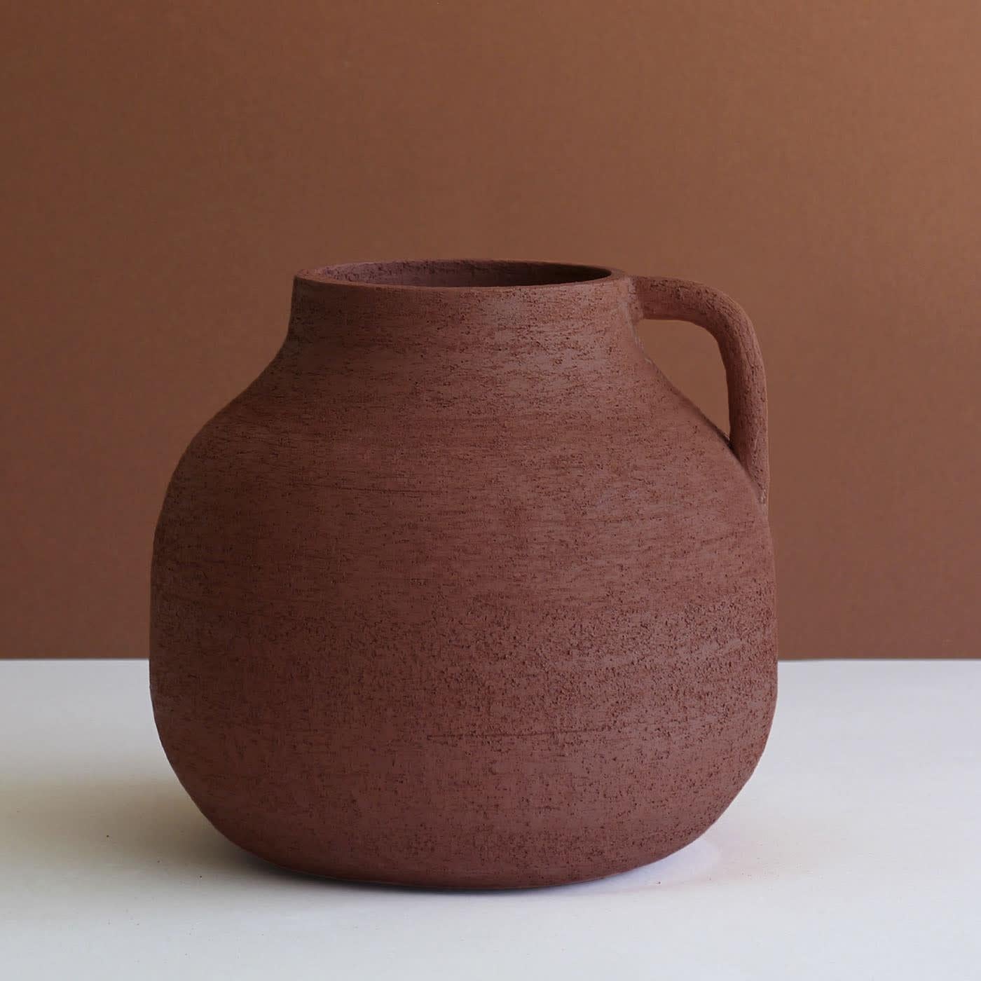 In dieser einzigartigen dekorativen Amphora trifft taktile Dynamik auf klare Linien. Die raffinierte, zerkratzte Textur wird aus Steinzeug hergestellt und in einem tiefen Rotton angeboten, der dem Interieur einen Hauch von Wärme verleiht. Die