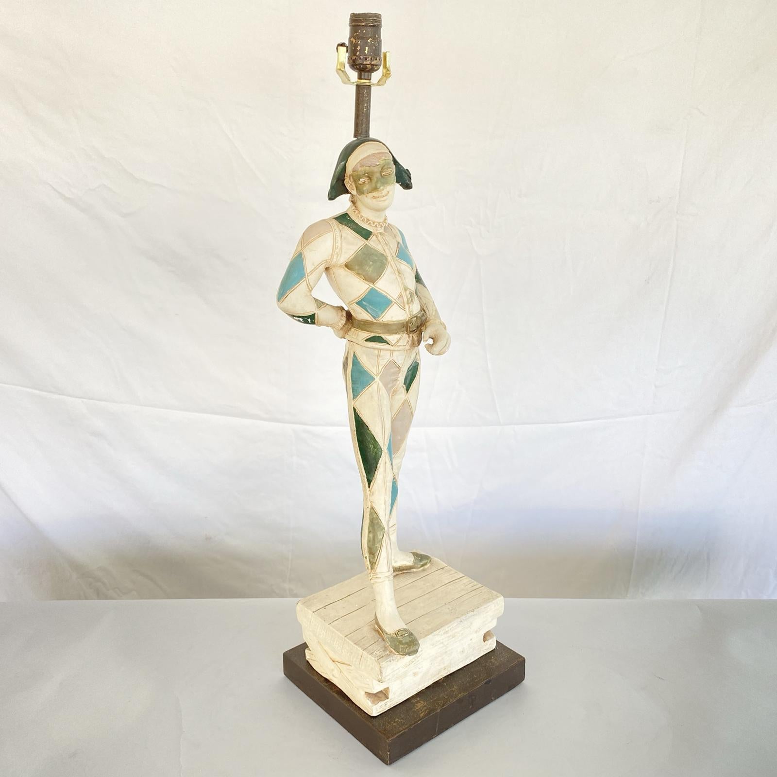 Lampe figurative unique de la Marboro Lamp Company, en plâtre peint à la main, formant un bouffon masqué, debout sur une caisse, montée sur une base en bois peint. 

Stock ID : D2993.