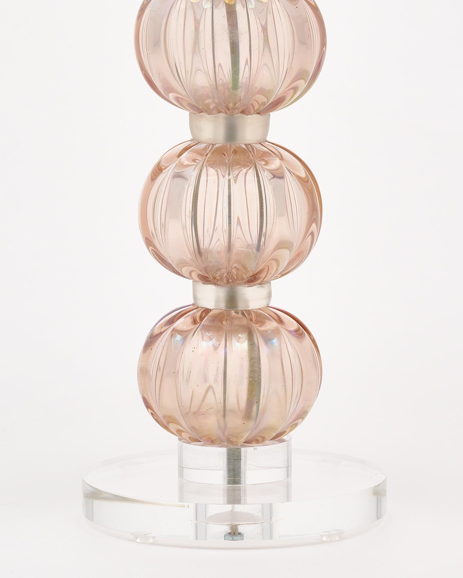 Single lamp from Murano, Italy made of hand-blown iridescent glass in a light pink color. The glass sits atop a Lucite base. It has been newly wired to fit US standards.
