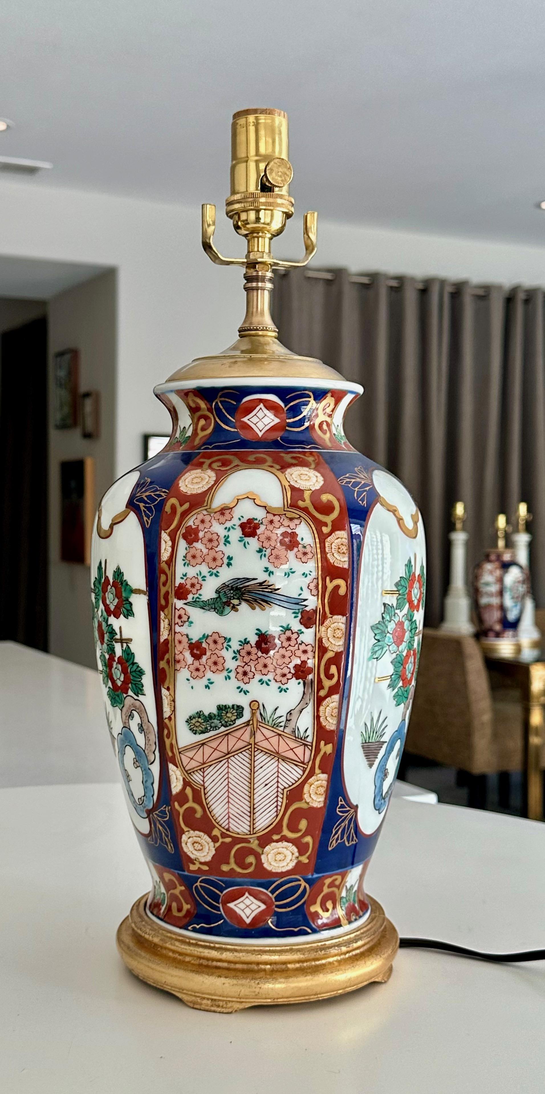 Vase unique en porcelaine japonaise Imari monté sur une base en bois doré avec un bouchon de vase en laiton. Les couleurs sont celles de l'Imari classique, avec un riche orange brûlé et un bleu foncé, accentués par des nuances de vert et d'or. Les
