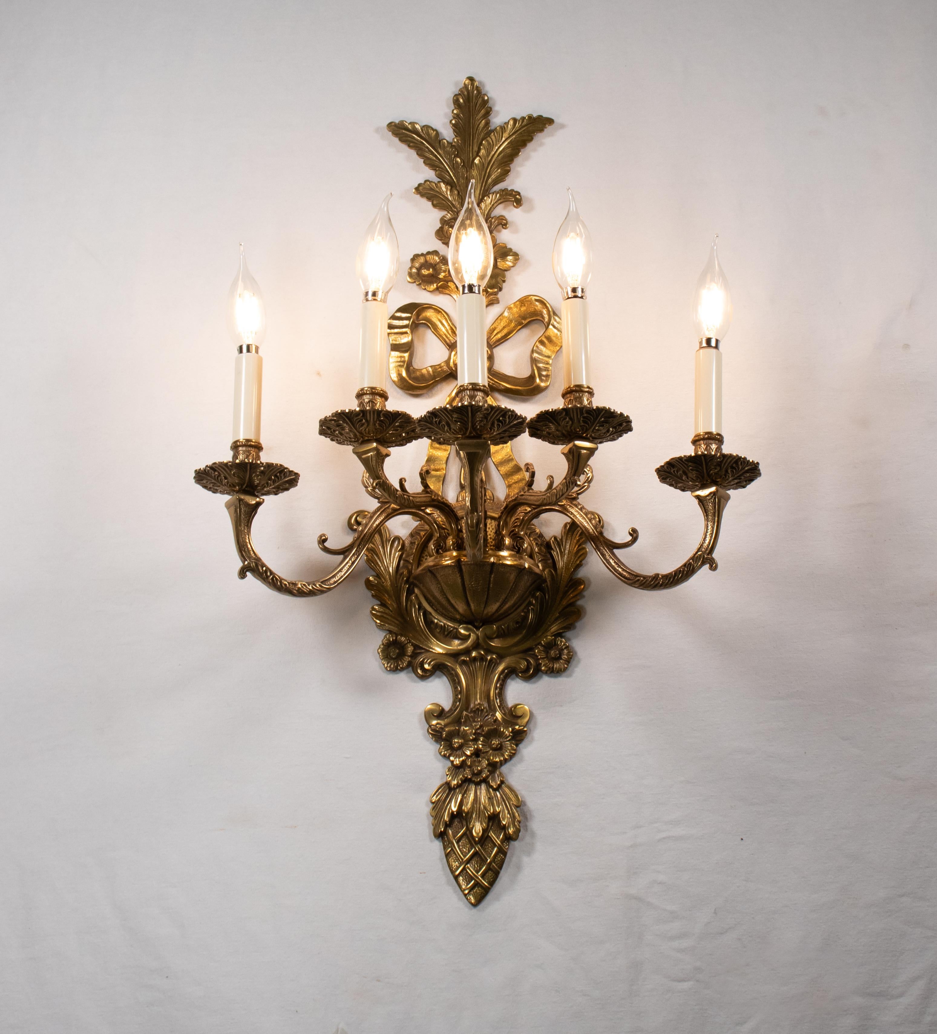 Este exquisito candelabro francés de principios del siglo XX, que ejemplifica el estilo Luis XV, está meticulosamente elaborado en bronce. Presenta cinco brazos de candelabro elegantemente curvados, cada uno de ellos diseñado para sostener luces de