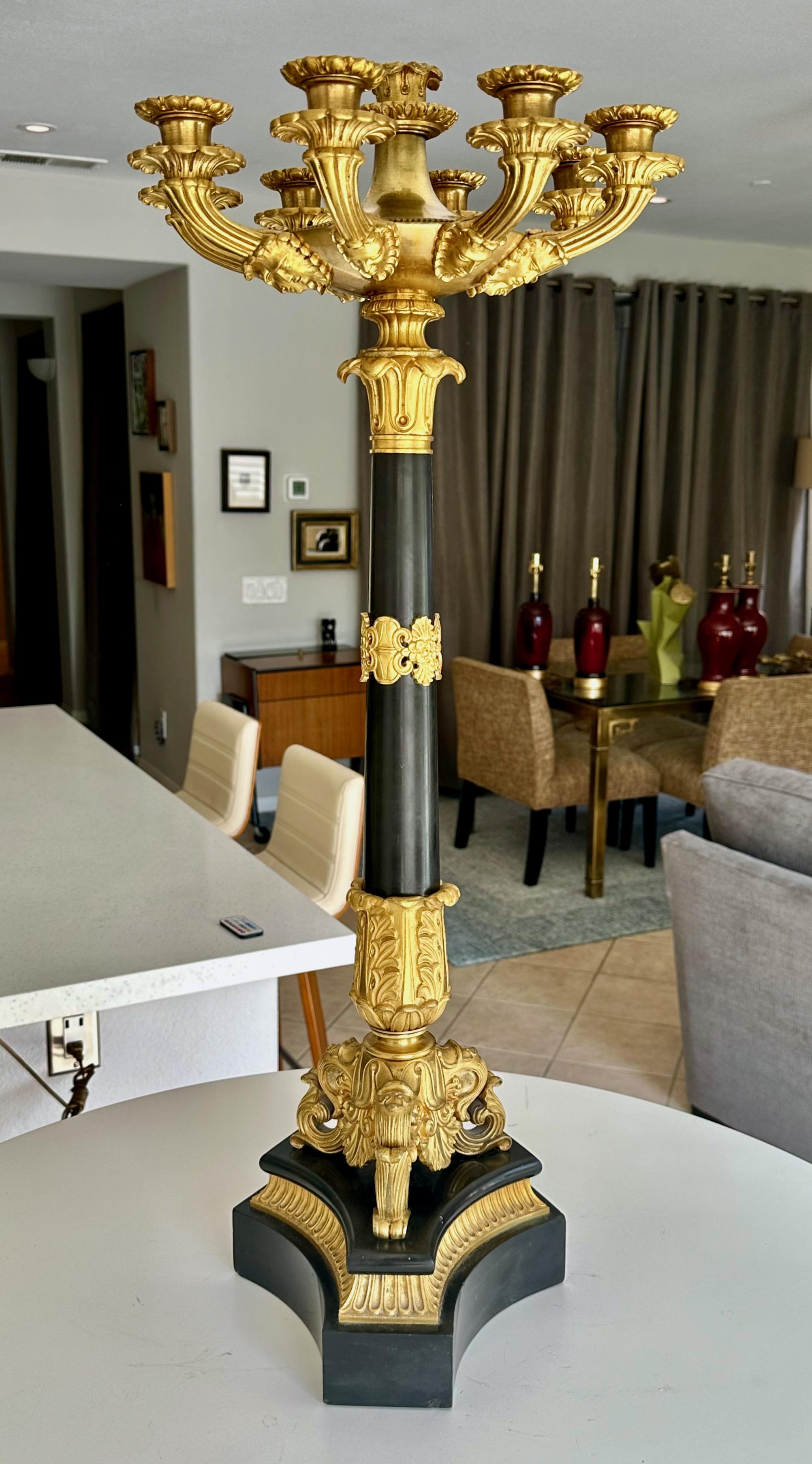 Singolo candelabro alto in bronzo dorato e ormeggiato del periodo della Restaurazione francese. L'ormolatura è molto dettagliata e finemente cesellata, il grande stelo centrale è in granito nero massiccio così come la base a tre lati. 