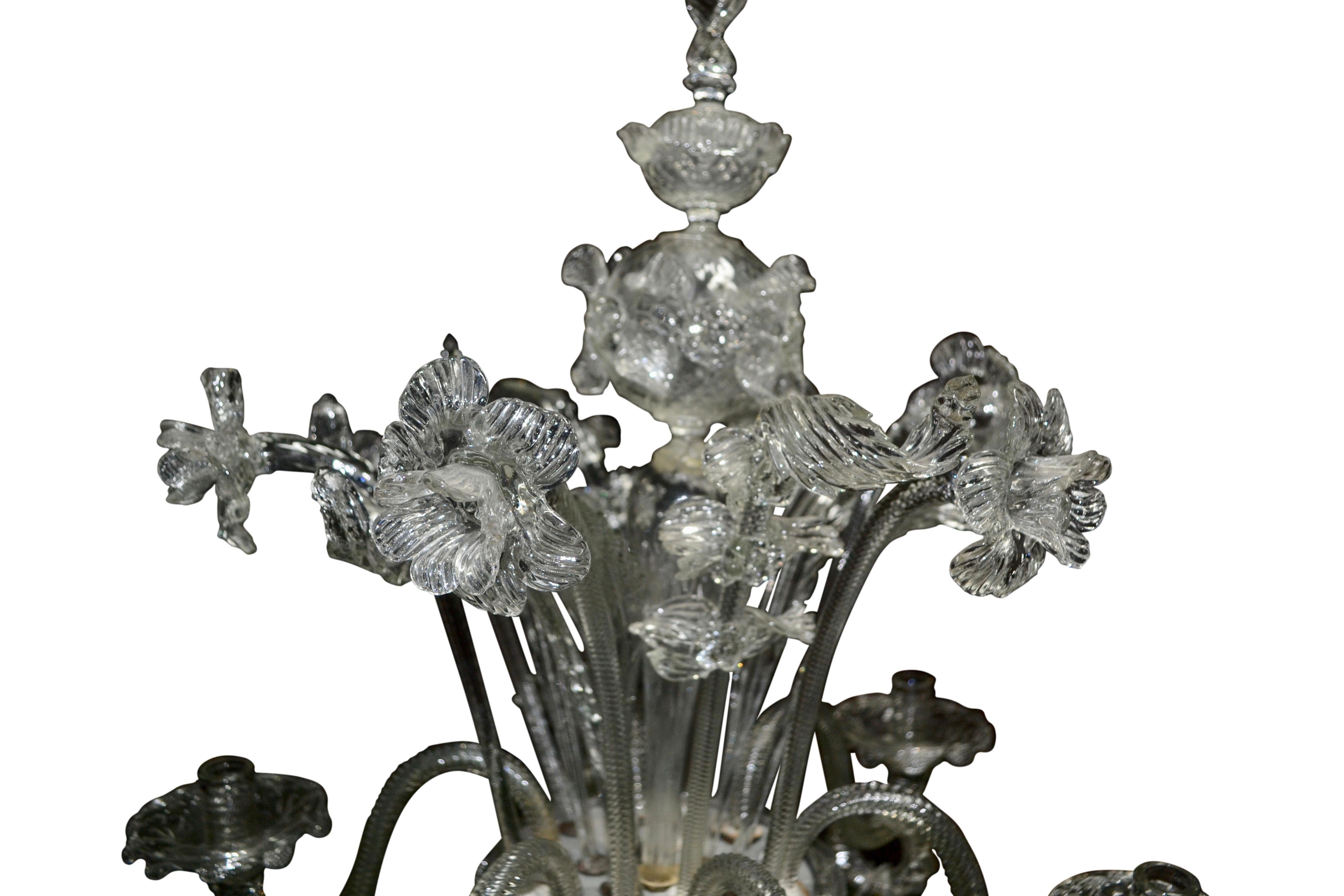 A clear glass single candelabra made in the Murano factory in Venice, circa 1930. The elaborately decorated column on a circular base supports a mid level bowl from which six 'S' shaped candle arms attach. Each arm is connected via a decorative