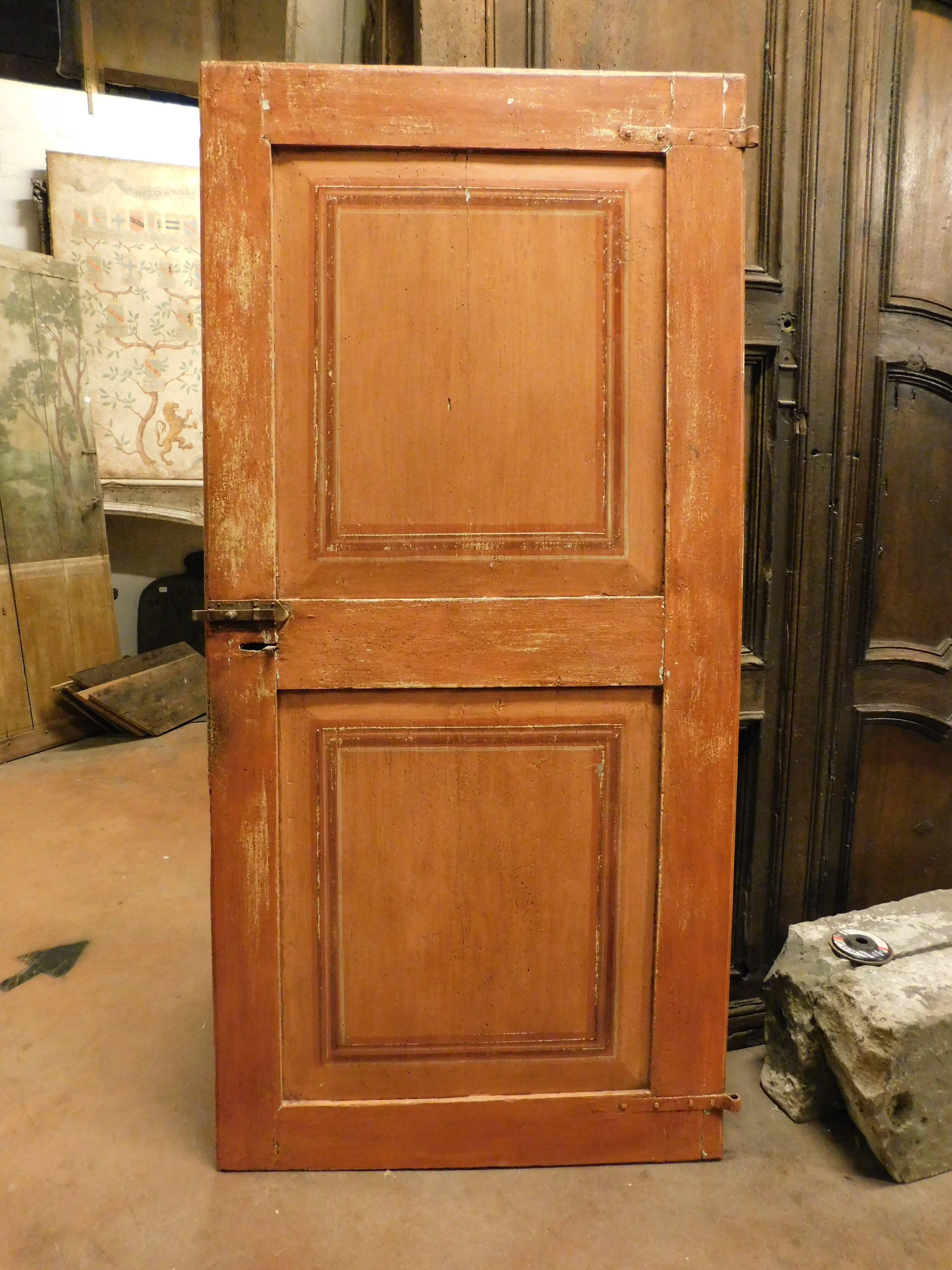 Puerta de interior sencilla, de una hoja en madera lacada naranja con cuadrados en los paneles pintados, de doble cara: dorso también lacado, apertura Pull, a la derecha, sin marco por haber nacido en la pared, pero aún con carraca de hierro