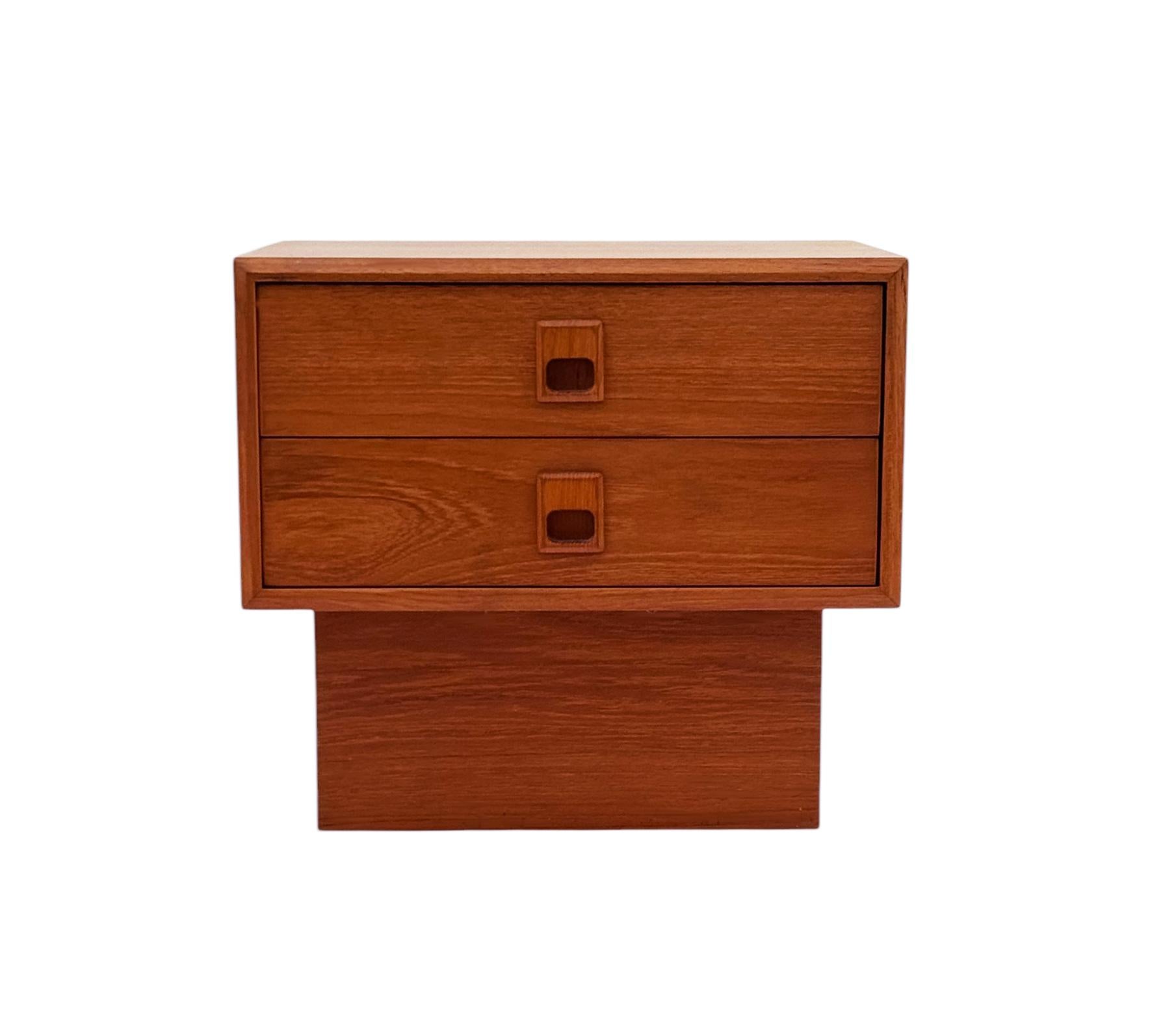1970s very unique & sleek Danish modern night stand in teak. It features beautiful wood grain, recessed handles & two drawers. 