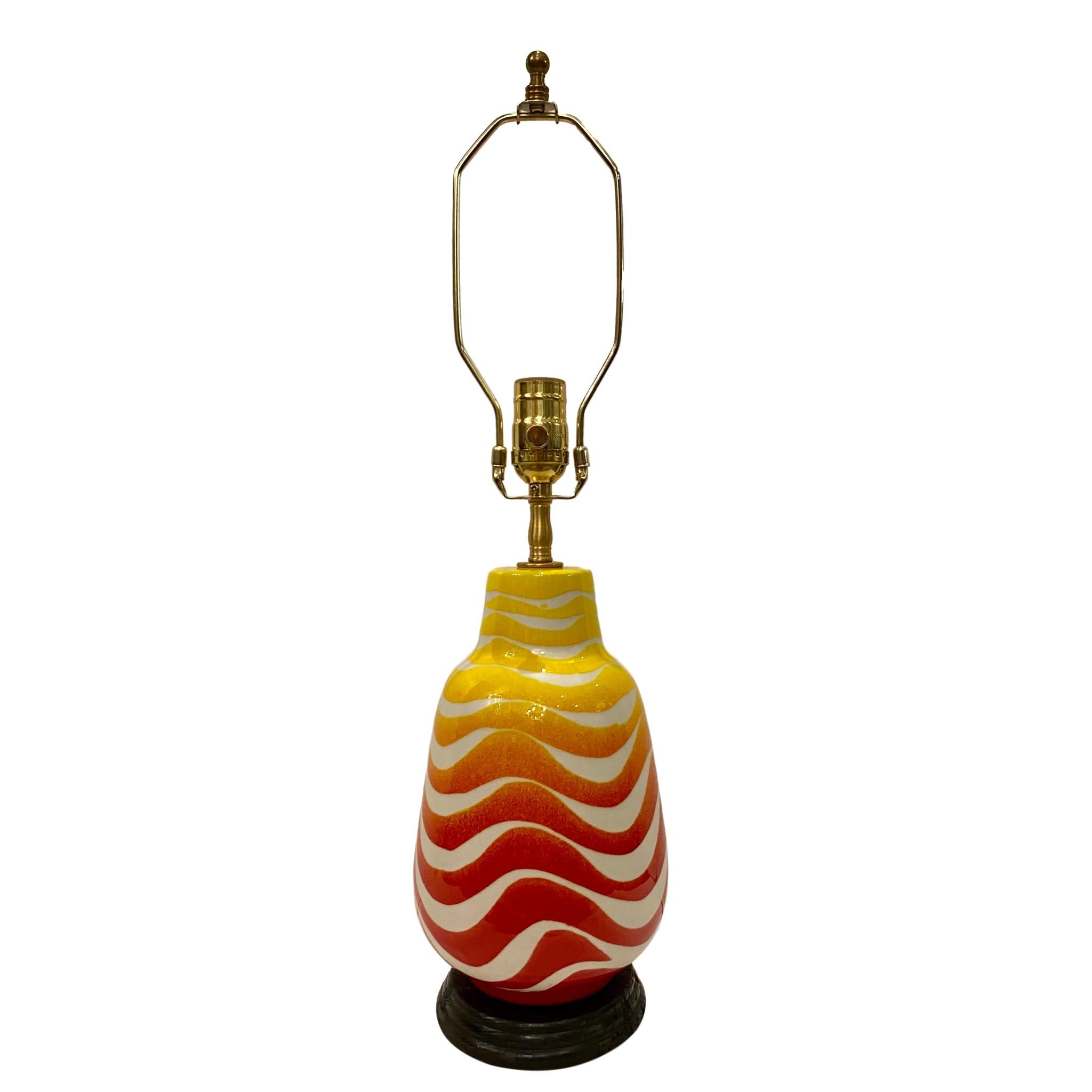 A single circa 1950's Italian glazed porcelain table lamp with a waves patterns of red and yellow on a white background.

Measurements:
Height of body: 11.5