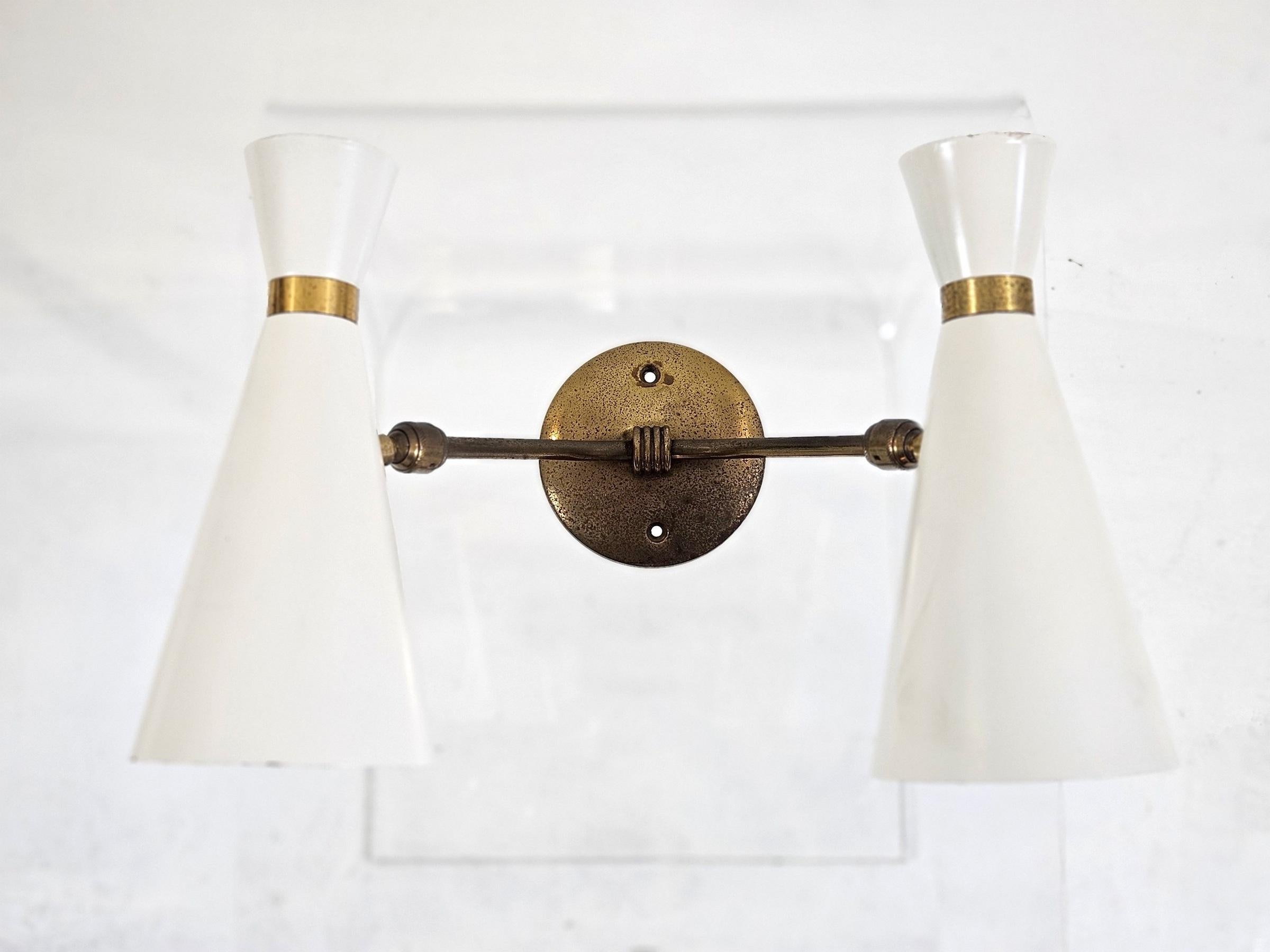 Aplique de pared de los años 50, blanco marfil y dorado, a la manera de Stilnovo Italia. Los dos conos de luz son ajustables en todos los ángulos. El revestimiento es nuevo y está en buen estado, y el latón se ha conservado tal cual, con signos de