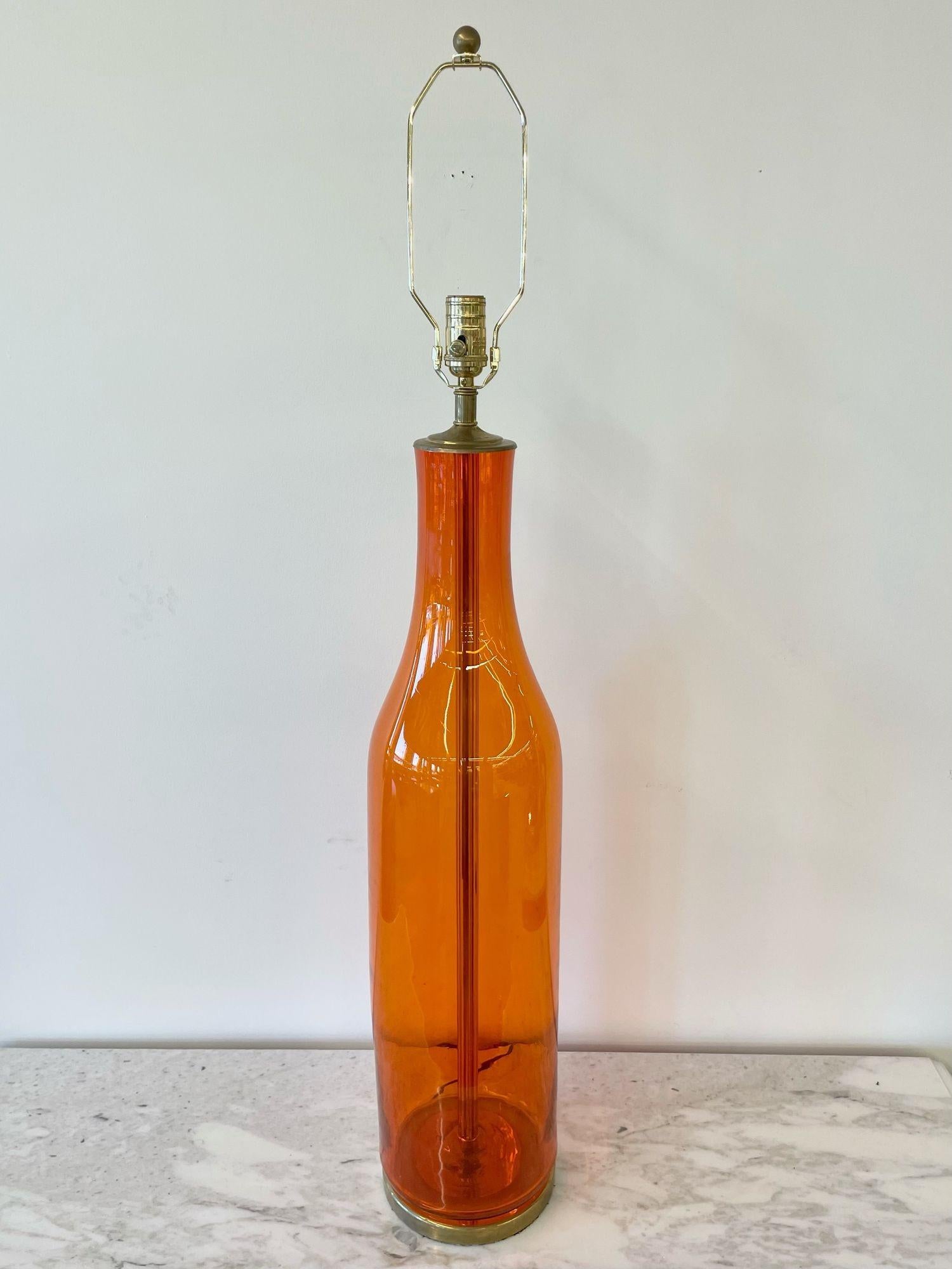 Single midcentury large orange blown glass bottle shape table lamp by Blenko
 
Blenko Large Orange Glass Lamp with Brass Hardware. Not sold with shade. 
 
Hand Blown Glass, Brass
United States, 1960s
 
44H x & 7Dia. Total
36H x & 7 Dia. (to