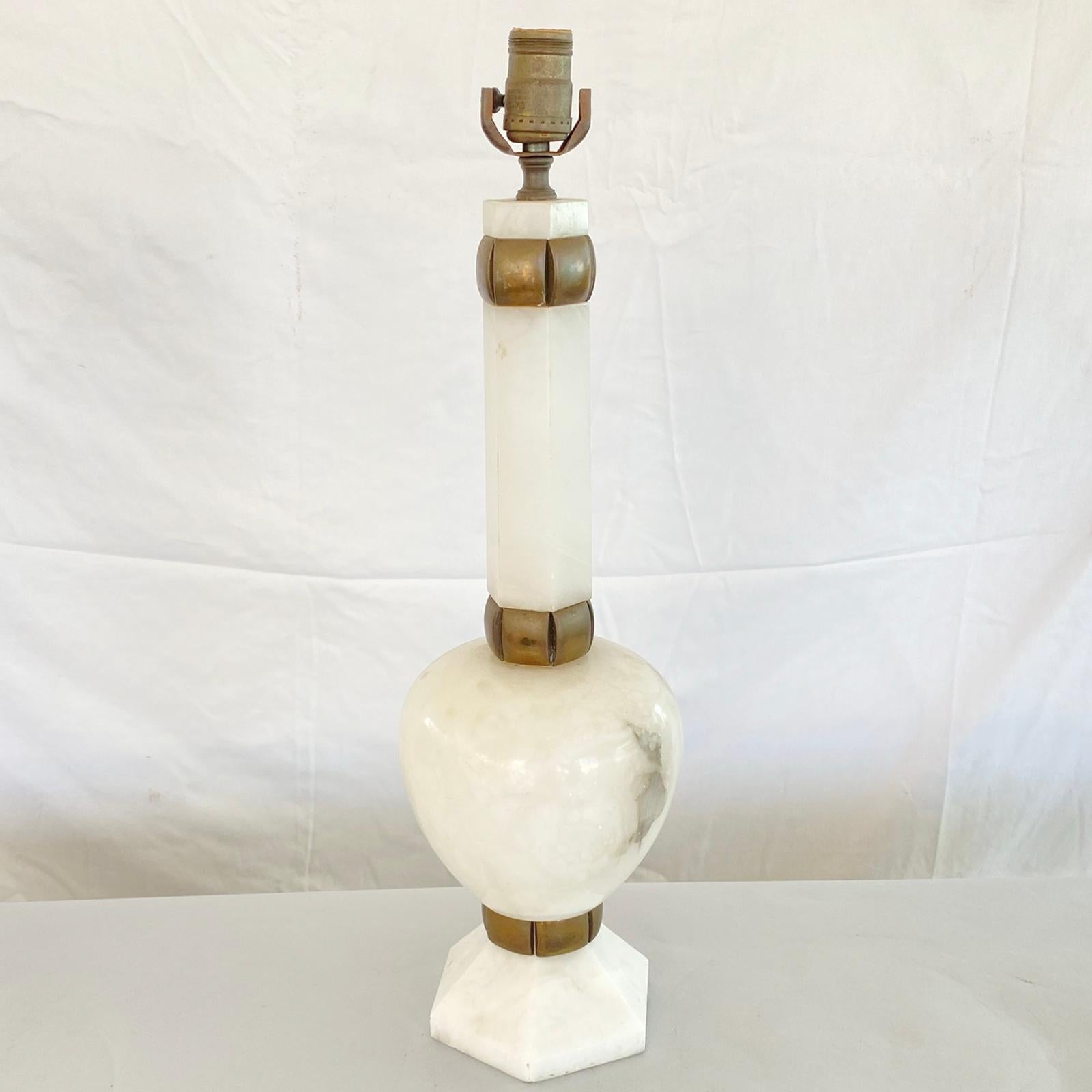 Single Hollywood Regency lamp of alabaster, having an ovoid body, with hexagonal neck and plinth, rounded brass collars adorn the joints of the neck and base, and have great patina. This lamp is very heavy, approximately 25 pounds. 

Stock ID: D2991 