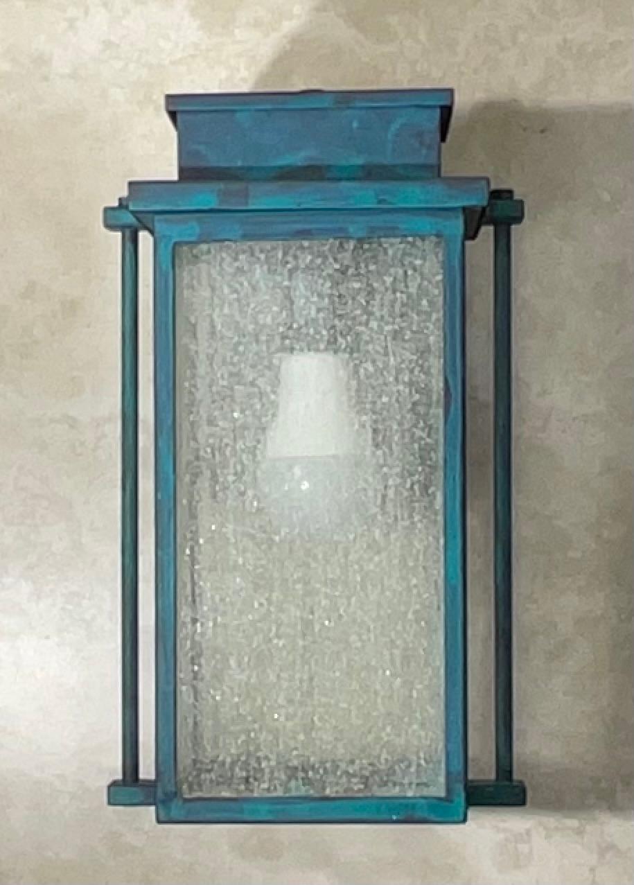 vats  your home's exterior with this single modern wall sconce,  Crafted from durable metal, this light fixture feature a unique hand verdigris patina finish, giving it a rich, weathered look with beautiful teal on protective black color tones. The