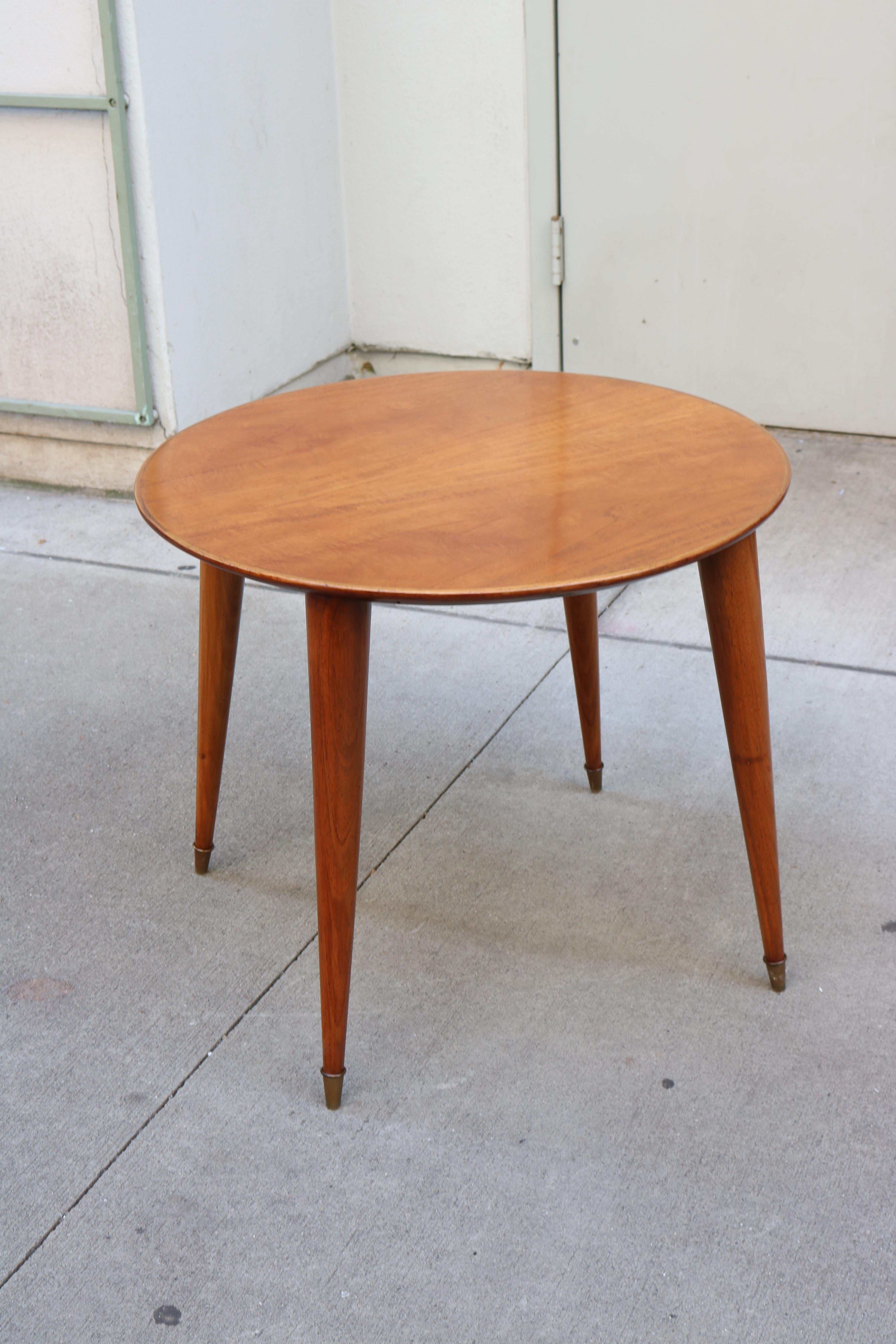 A round top side table in beechwood. 
Table resting on four legs ending in decorative brass sabots.