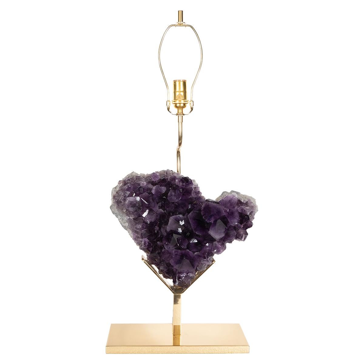Single brass table lamp with custom frame supporting a massive heart-shaped natural amethyst fragment.