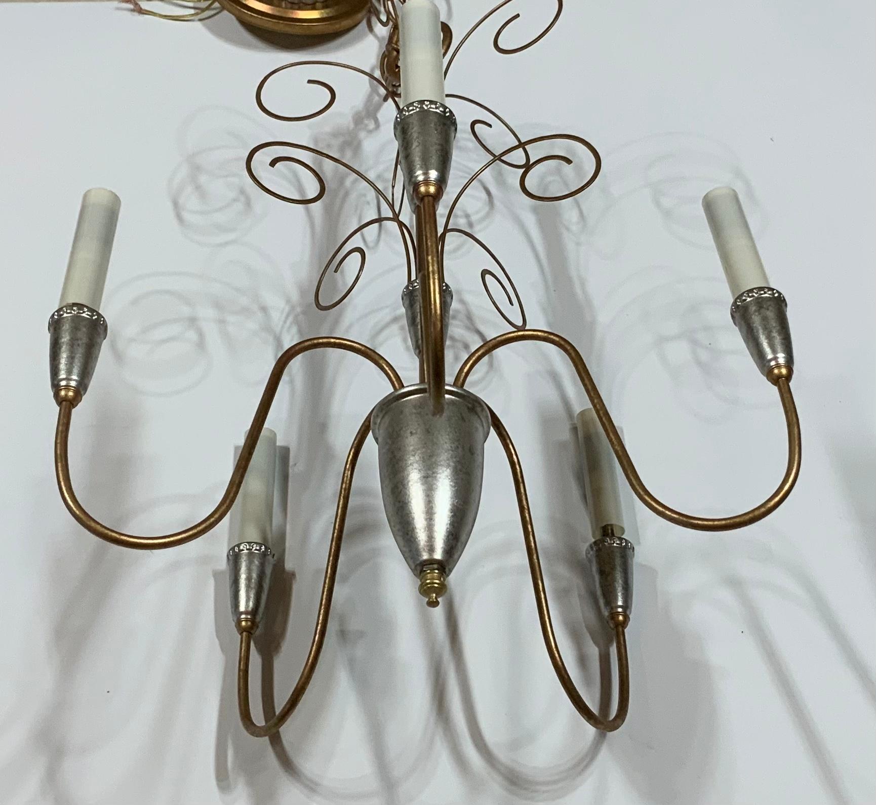Elegant chandelier made of metal , painted in silver and gold ,with five stems 60/watt light each stem 
Electrified and ready to use. Beautiful and clean cut chandelier for any room 
One more is posted
Original canopy and chain included.
  