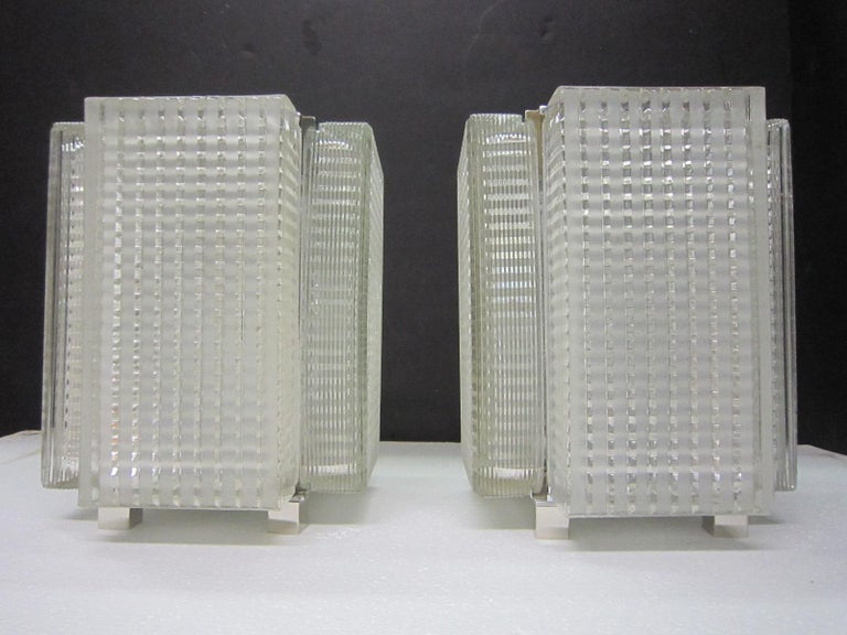 A pair of Midcentury reticulated glass table lamps with nickeled trim.
Four heavily molded art glass panels of rectangular form create this Minimalist glass structure.
Highly architectural in overall form with motif of interlacing lines in a