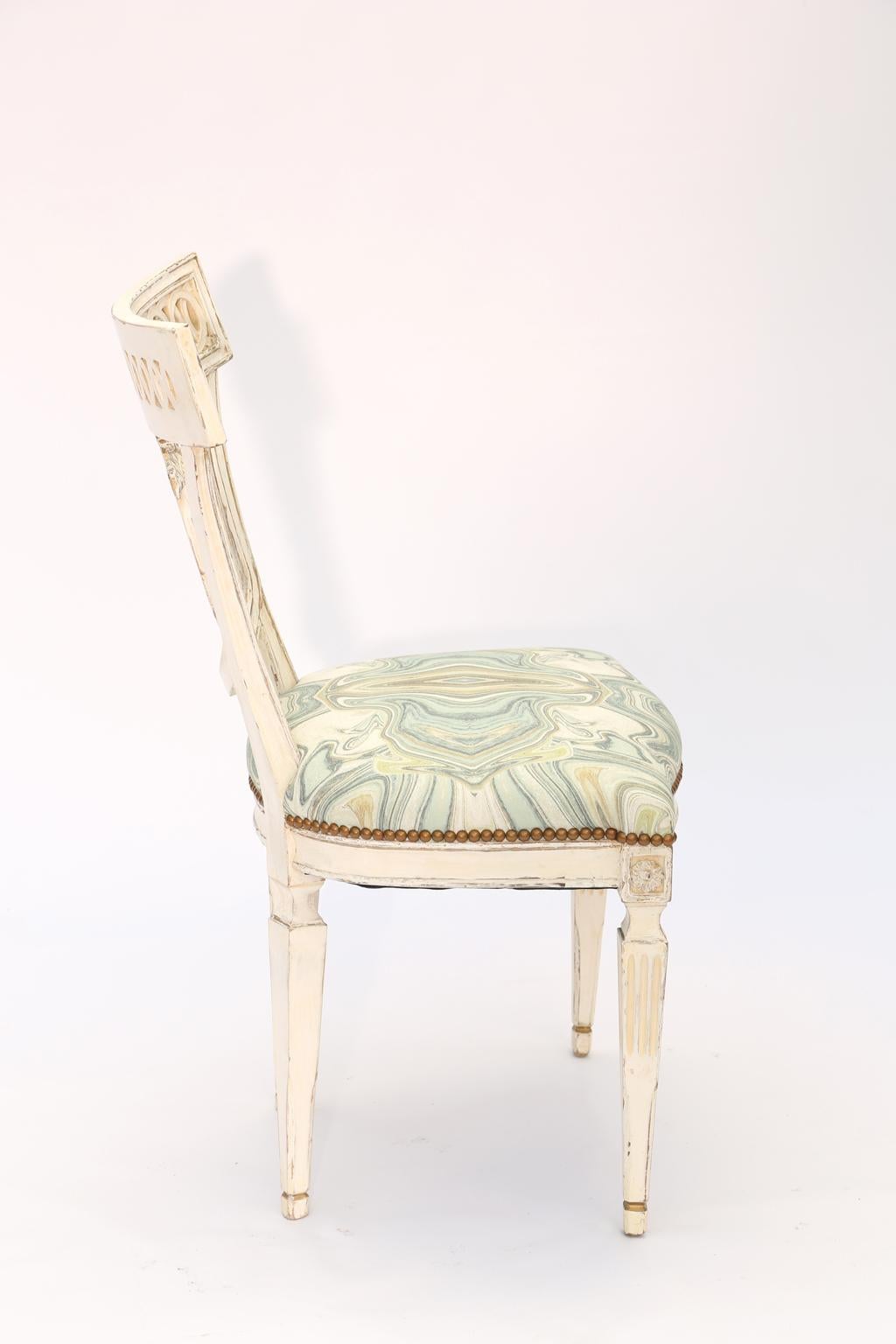 Side chair, having a painted finish, its toprail with pierced guilloche design, the spat a beaded, oval, cartouche, surmounted by a bow, its crown seat upholstered with nailheads, raised on square-section, tapering, fluted legs.

Stock ID: D1680.