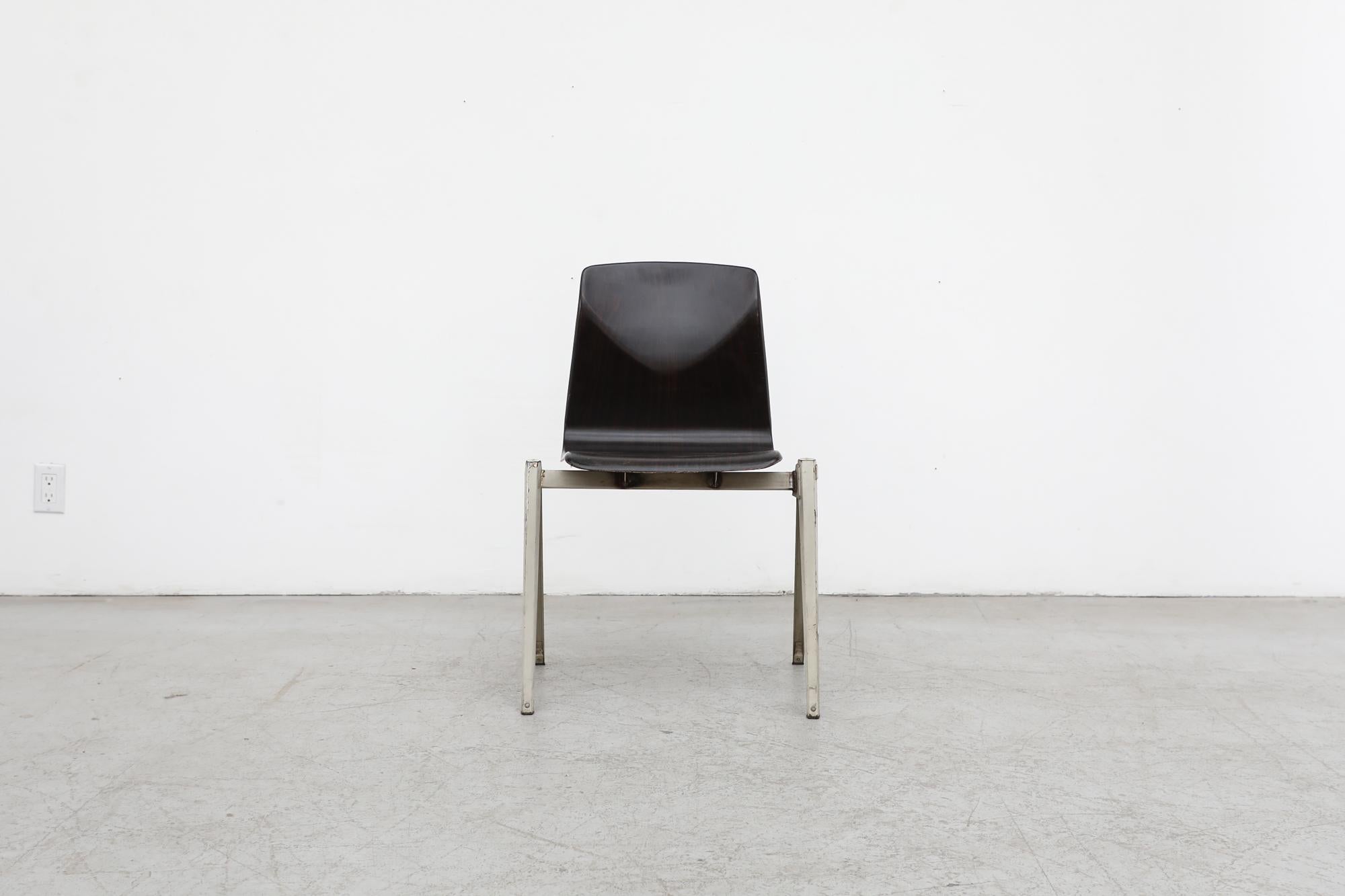 Single Prouve Style Industrial Stacking Chair with dark stained laminate wood shell seat and grey enameled metal frame. In original condition with visible frame wear and scratching consistent with its age and use. Others listed in various colors