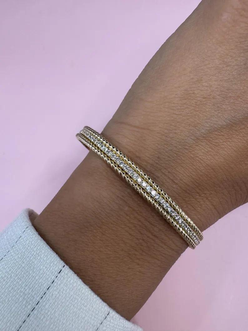 Bracelet bangle en or jaune 14 carats présentant une rangée centrale de 50 brillants ronds pesant 0,98 carats avec une garniture tressée, 18,48 grammes.
Couleur I-J
Clarté VS2

Plein de vie et d'éclat. 
Plus de Bangles en stock. 
Disponibles en