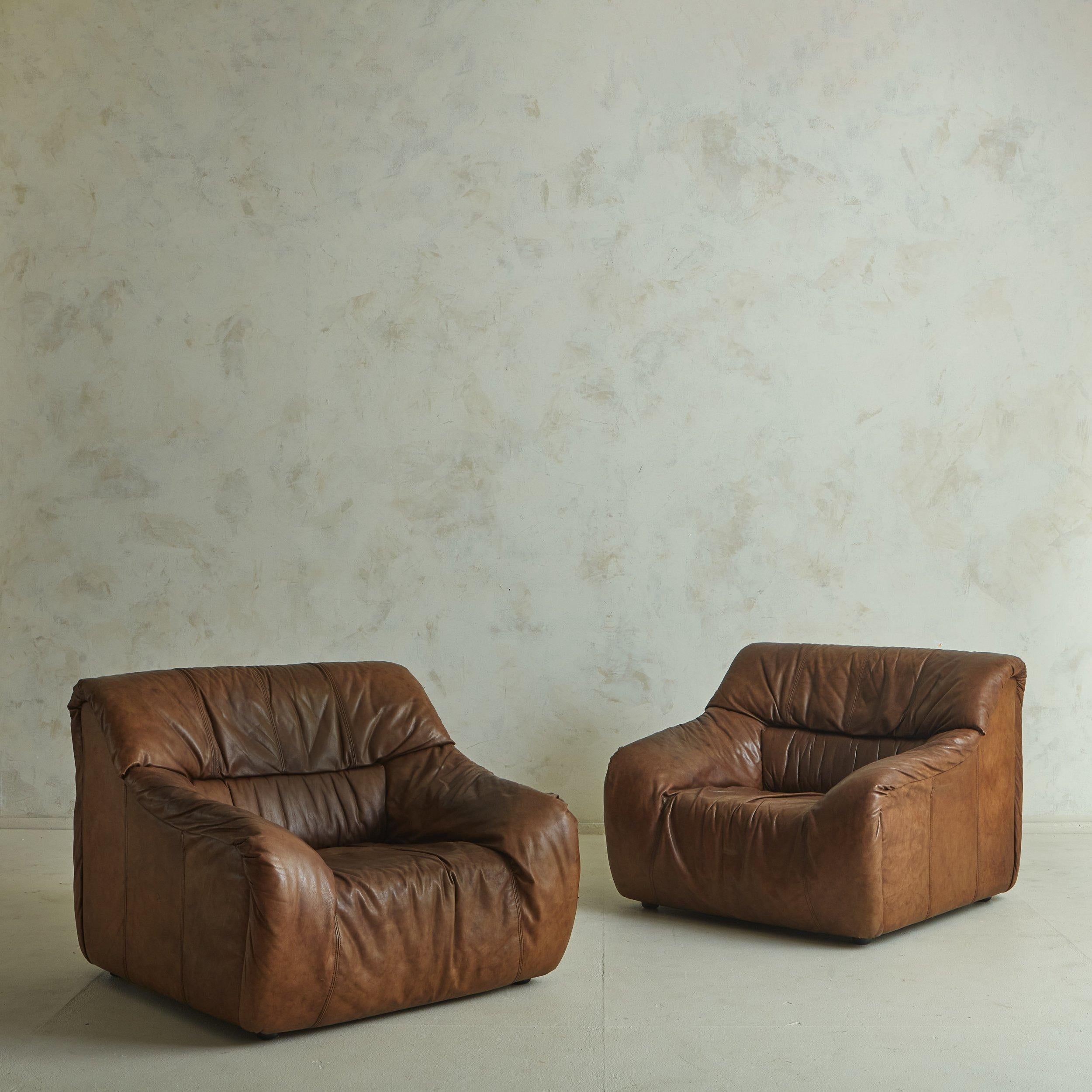 Französischer Sessel aus den 1970er Jahren im Stil von De Sede. Dieser majestätische Stuhl hat einen Blockrahmen mit geschwungenen Armlehnen und steht auf runden Acrylfüßen tief am Boden. Die Originalpolsterung aus schokoladenfarbenem Rüschenleder