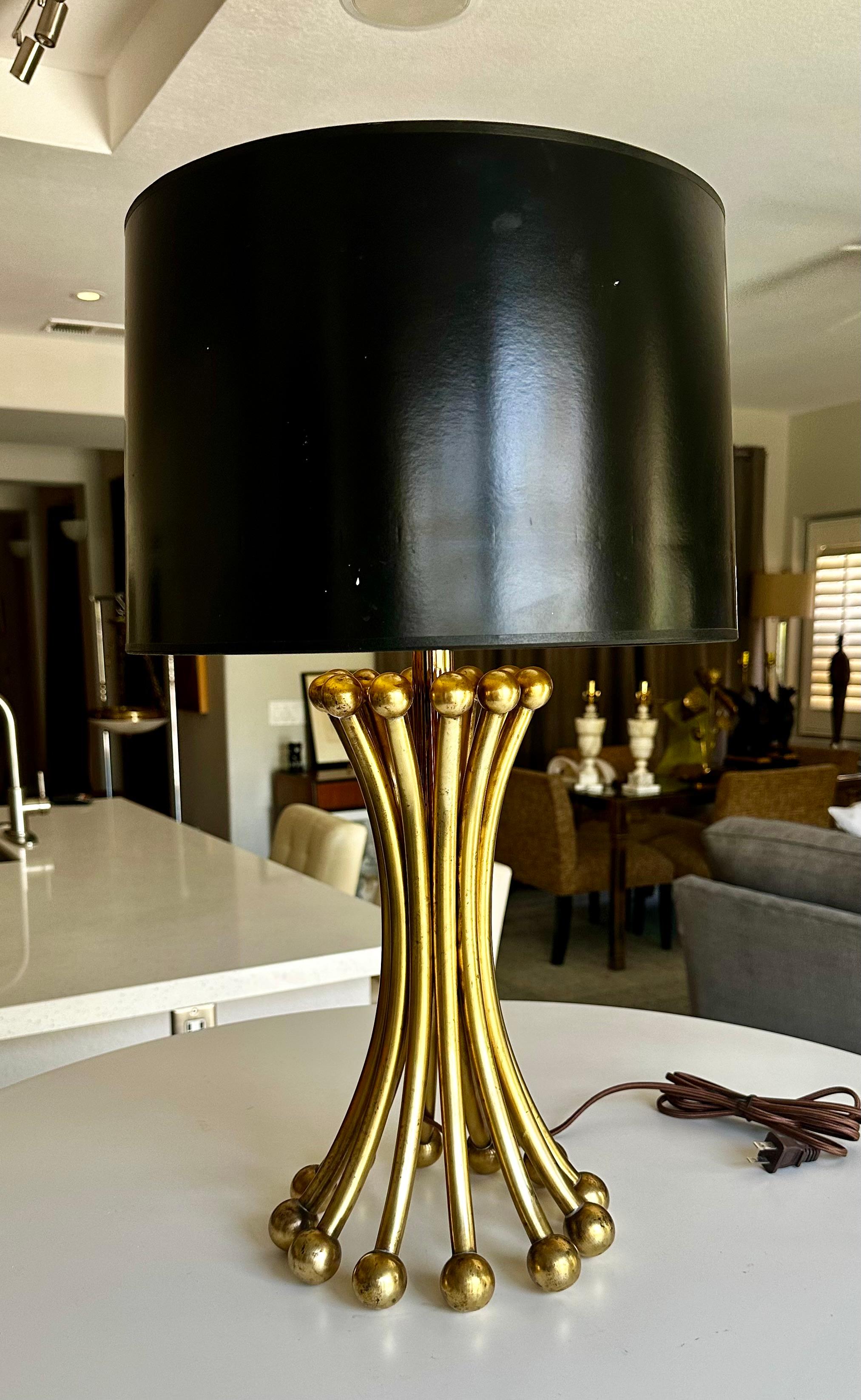 Lampe de table en laiton massif, de fabrication artisanale et experte, en forme de bouquet corseté de tiges en laiton massif munies aux deux extrémités de boules en laiton massif. Câblage neuf avec prise à 3 voies et cordon en rayonne. 
La forme