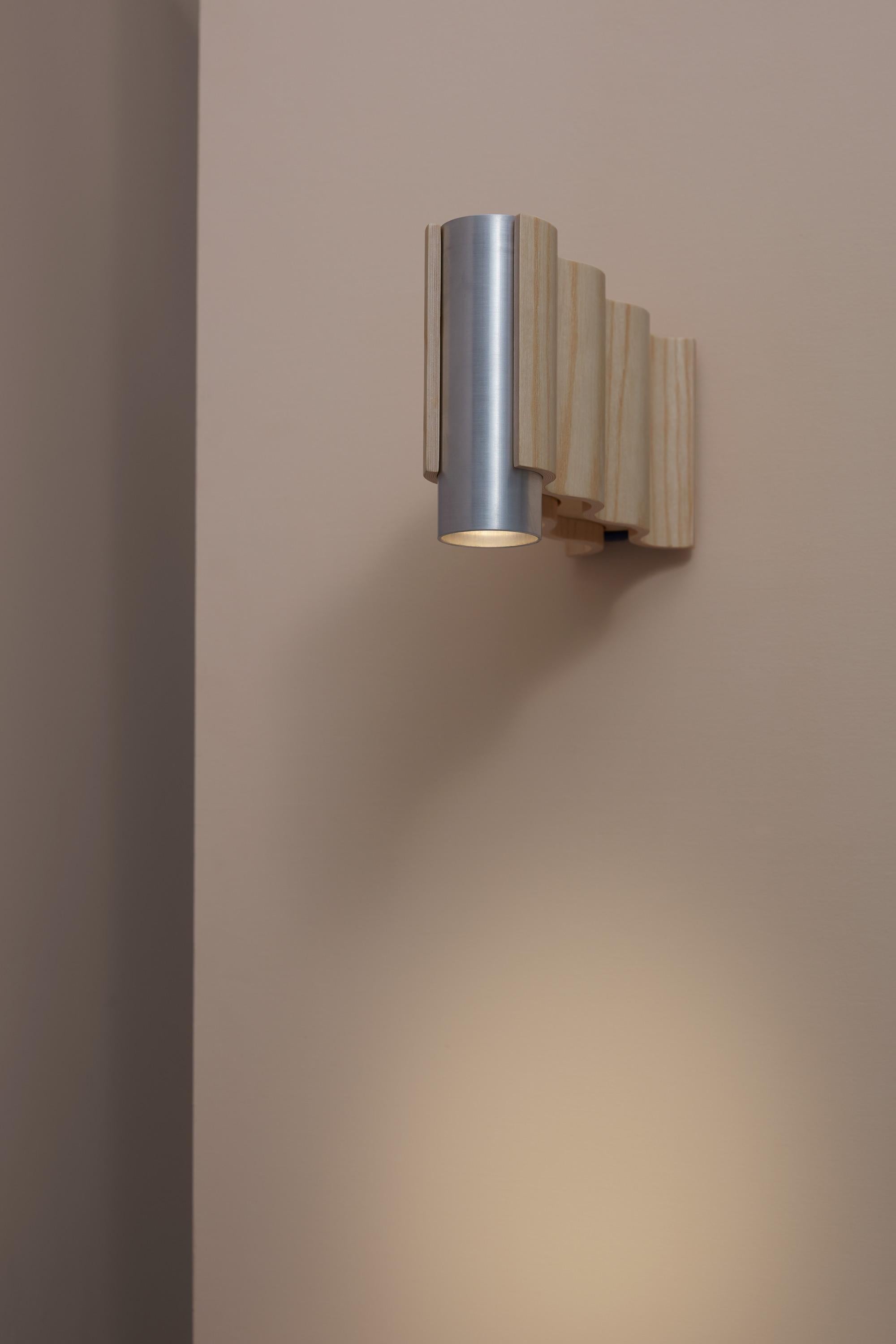 Single sconce spot light made from natural ash veneered plywood (clear coated) and brushed aluminium tube.

Technical information:
- Comes with dimmable spot light (3.6W, 300 Lumen, 3000° Kelvin, 36 degree beam angle)
- Wired for a 230/220V or 110V