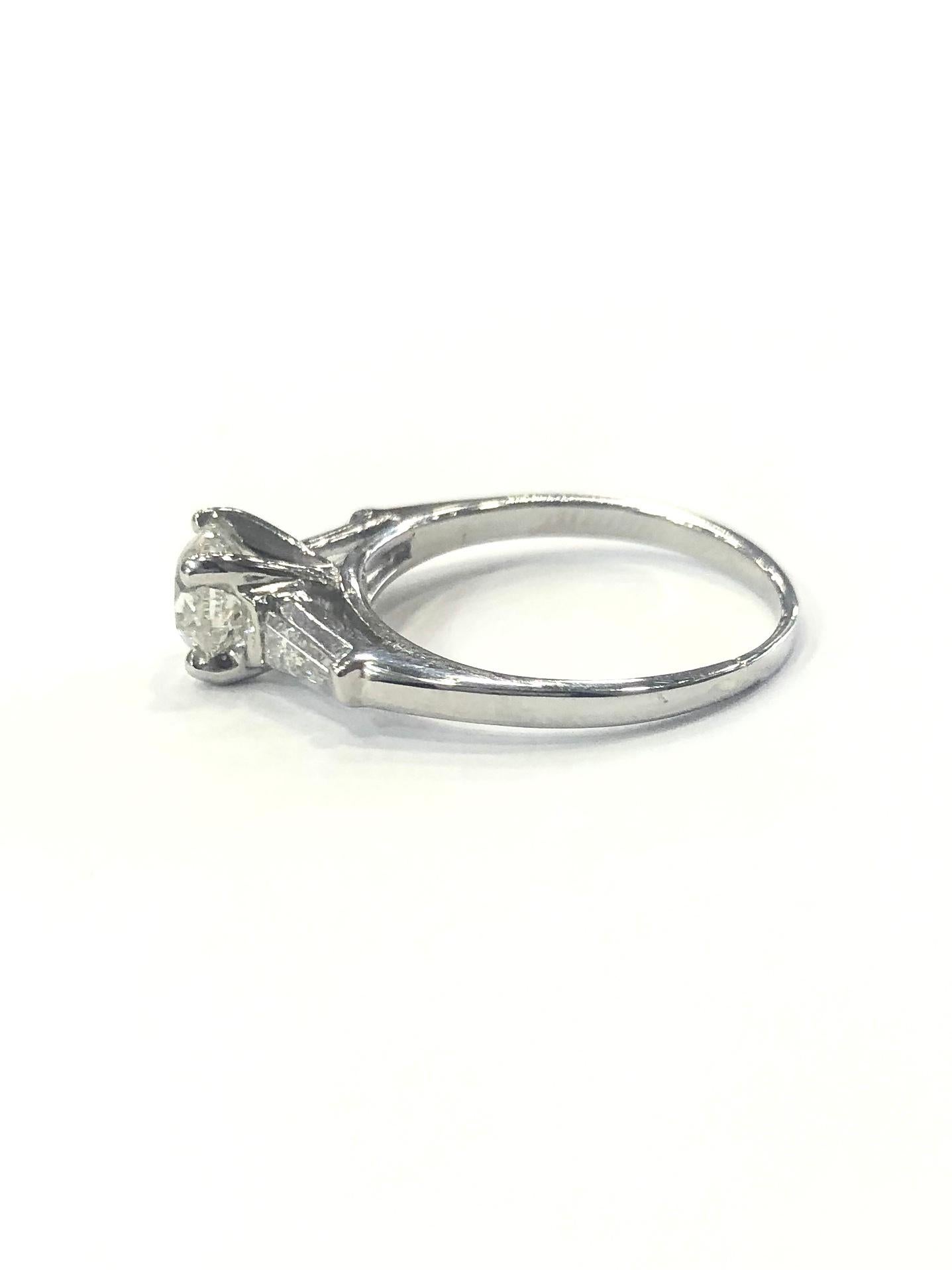 Platinum Certified Single Stone Diamond Engagement Ring. Set with one certified round brilliant cut diamond set in a four claw setting.
Set with two tapered Baguette diamonds diamonds on the shoulders. (one each side)
Edwardian style.

International