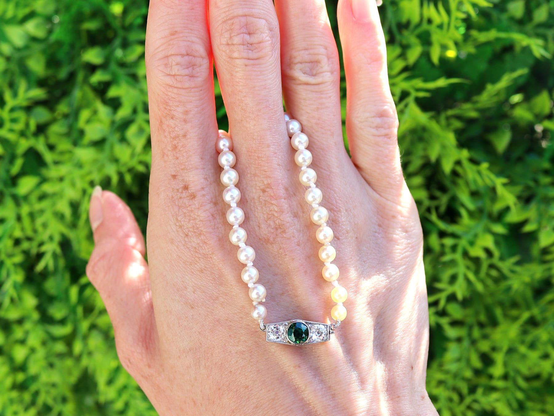 A fine and impressive single strand pearl necklace with 0.66 carat green sapphire and 0.88 carat diamond and 12k white gold clasp; part of our diverse collection of pearl necklaces. 

This fine and impressive single strand pearl necklace with