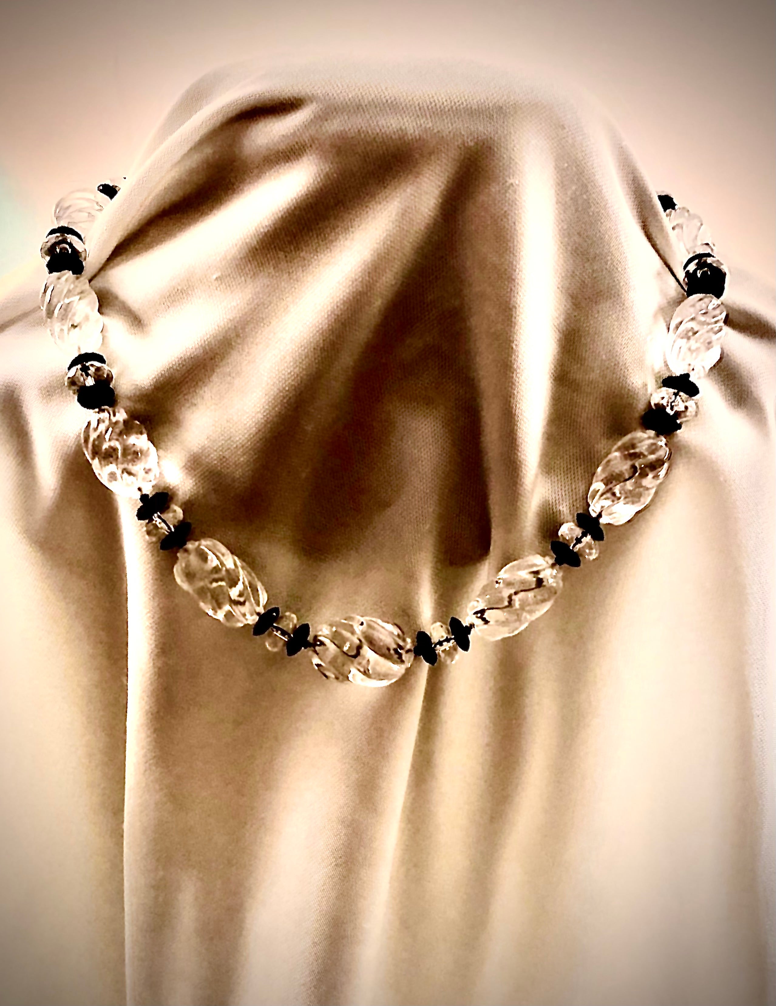 Beautiful, shimmering vintage swirl carved rock crystal torchons interspersed with faceted rock crystal rondelles. The rondelles are flanked on either side by saucer shaped discs of black onyx. The necklace is finished with macrame cord terminating
