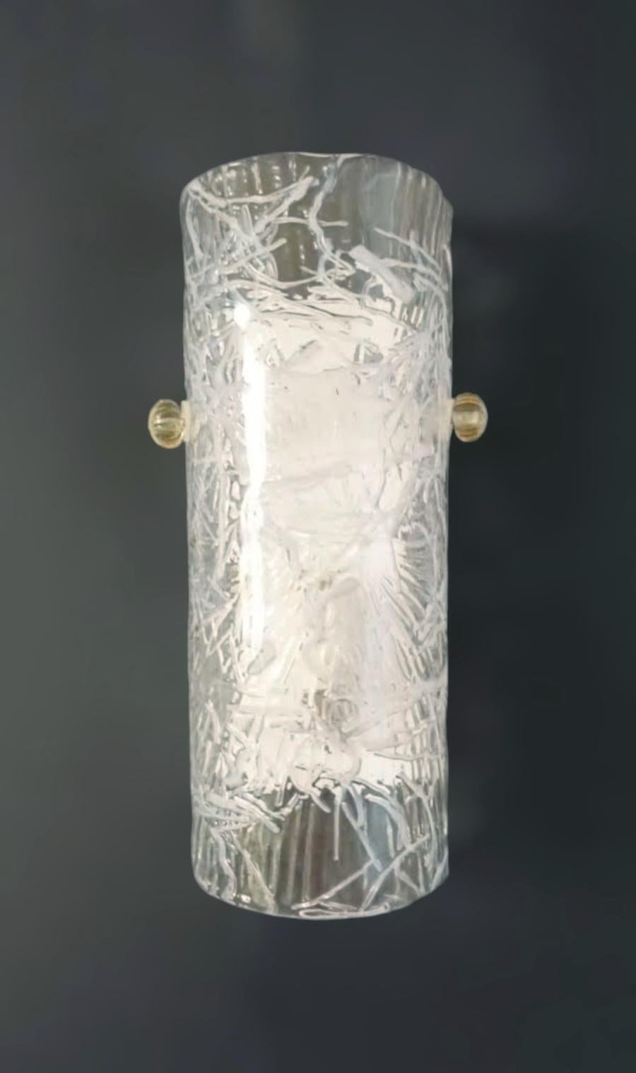 Italienische Wandleuchte mit einem zylindrischen Murano-Glasschirm in klarer Farbe mit weißer Textur, montiert auf weißem Metallrahmen / Made in Italy by Mazzega 1970er
Maße: Höhe 12 Zoll, Breite 6 Zoll, Tiefe 3,5 Zoll
1 Leuchte / Typ E12 oder E14 /