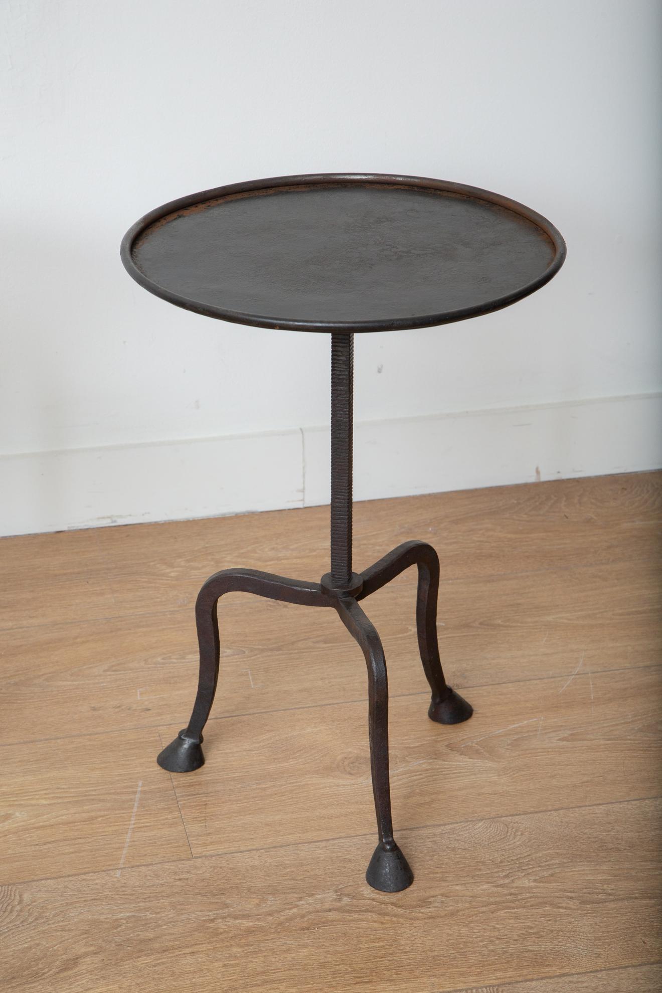 Tavolino treppiede forgiato a mano, in stock.
Questo splendido tavolino a treppiede in ferro battuto con gambe a zoccolo è un'aggiunta accattivante a qualsiasi arredamento di casa. Il suo piano rotondo è dotato di un labbro e la sua struttura in