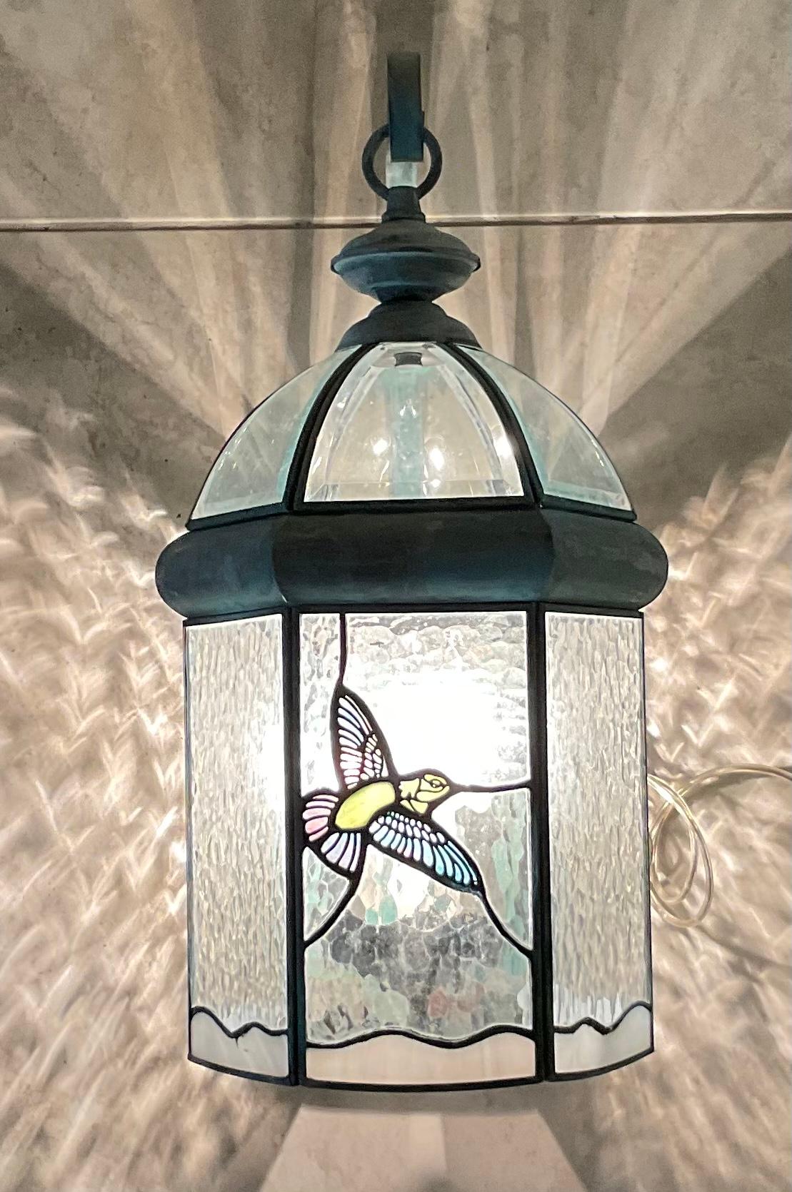 Funky vintage wall lantern handcrafted from solid brass, seeded glass, and three 40/watt lights suitable for wet location. Artistic glass bird motif on front.