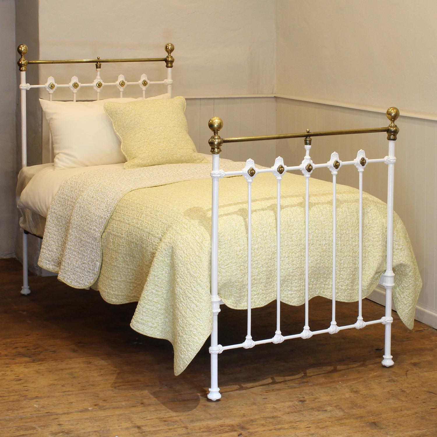 An attractive Victorian antique bed painted in white, with straight brass top rails and ornate castings decorated with dainty brass rosettes on the head and foot board. 
This bed takes a standard UK single 3ft wide x 6ft 3in long base and mattress,