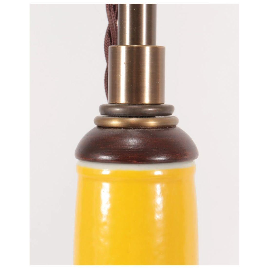 Une lampe gourde vintage en porcelaine jaune avec un cou élancé et un fond rond dans une belle nuance de jaune ensoleillé.   Deux douilles d'ampoules, chacune dotée d'une cordelette individuelle, assurent un éclairage suffisant.  Un interrupteur