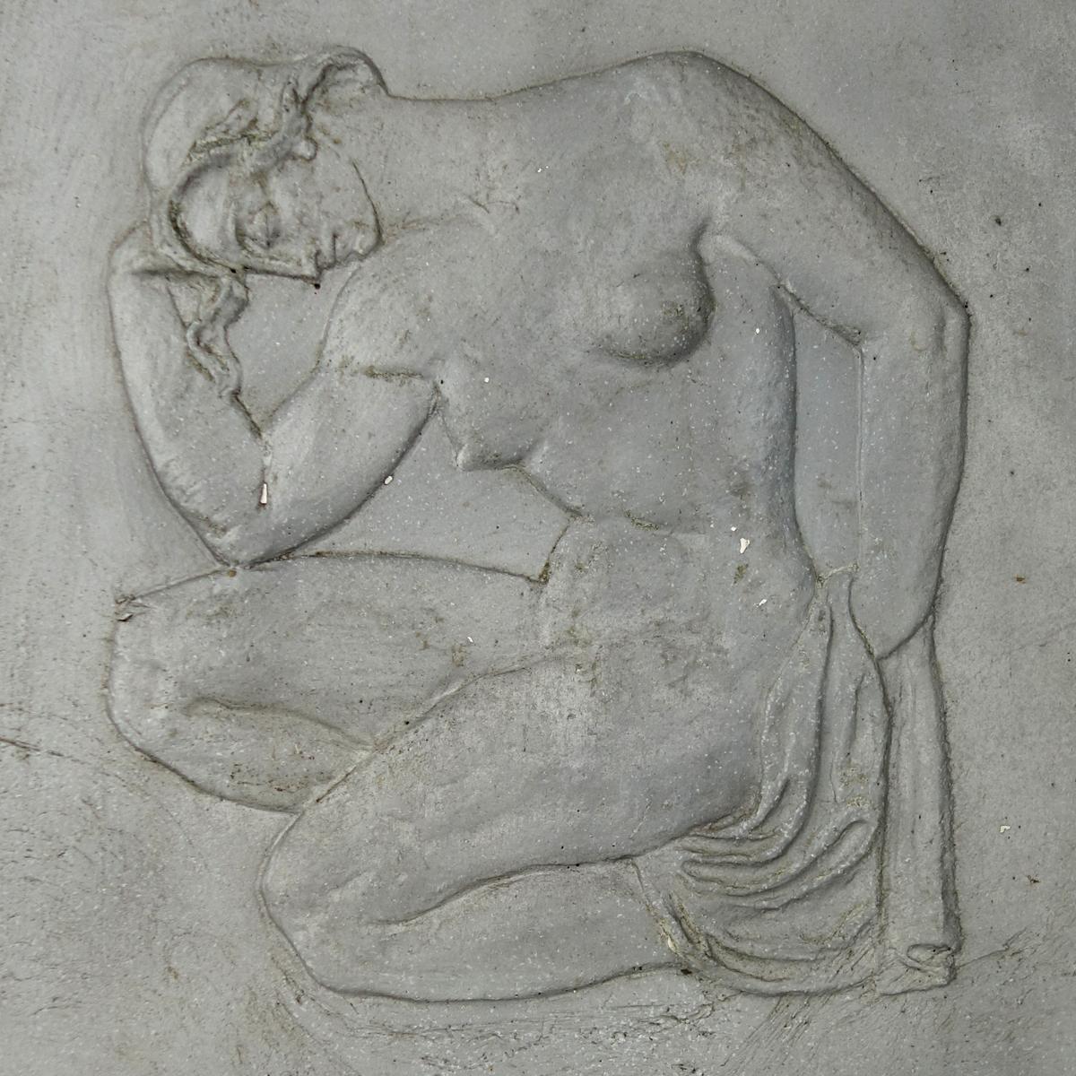 This plain and austere plaquette shows us a muscular Roman young man wearing just a loincloth. Squatting on the ground he sits, in the typical position of the Le Penseur artwork by Rodin, in a brown study.
The plaquette originates from the facade