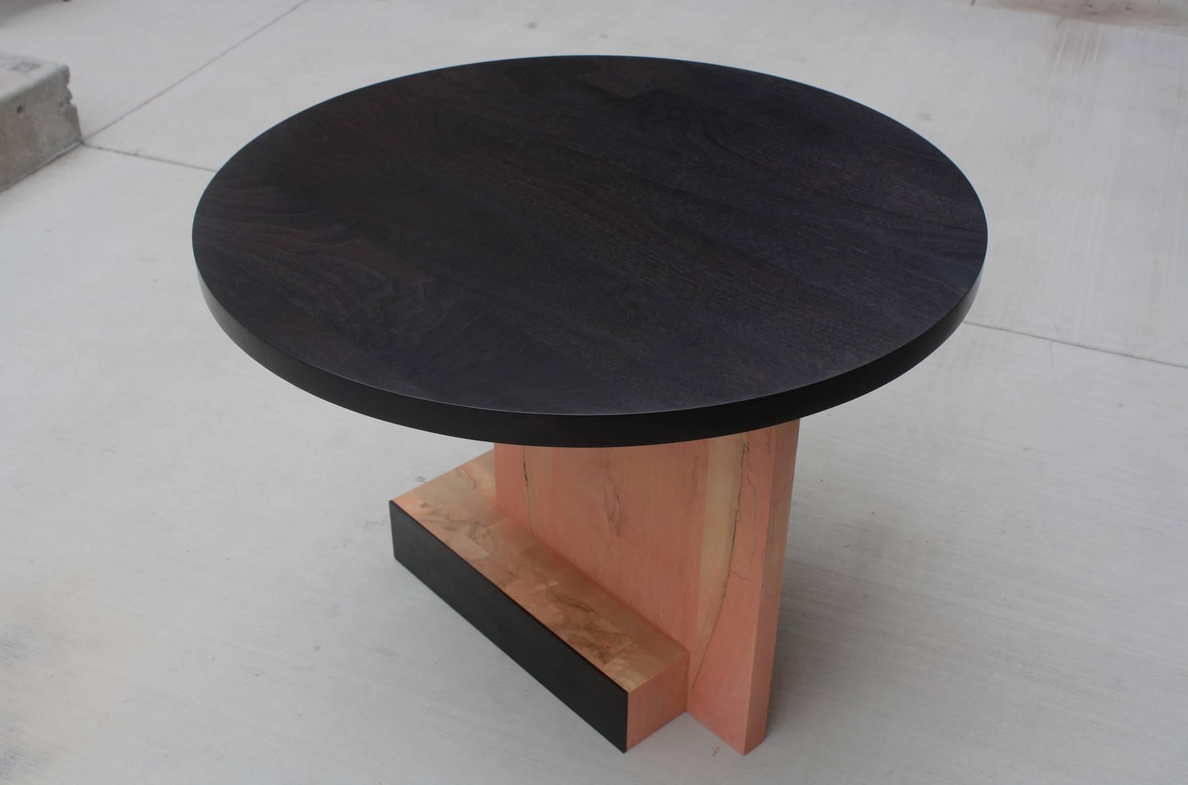 Handmade in Chicago by Laylo Studio, this customizable dining table features a round table top on an asymmetric butcher block base clad with metal panels. The solid wood butcher block base is punctuated by a vertical panel set decidedly off center