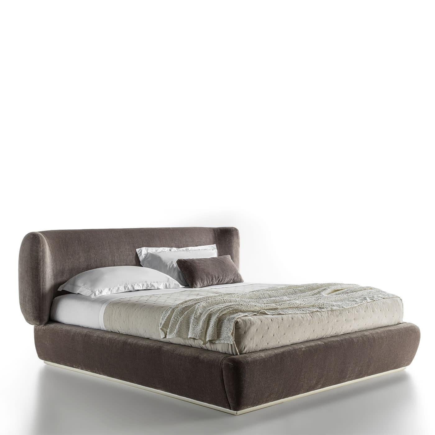 Upholstered bed characterized by the softness of the volumes. Bed base and mattress are not included. Upholstery available in different fabrics upon request.