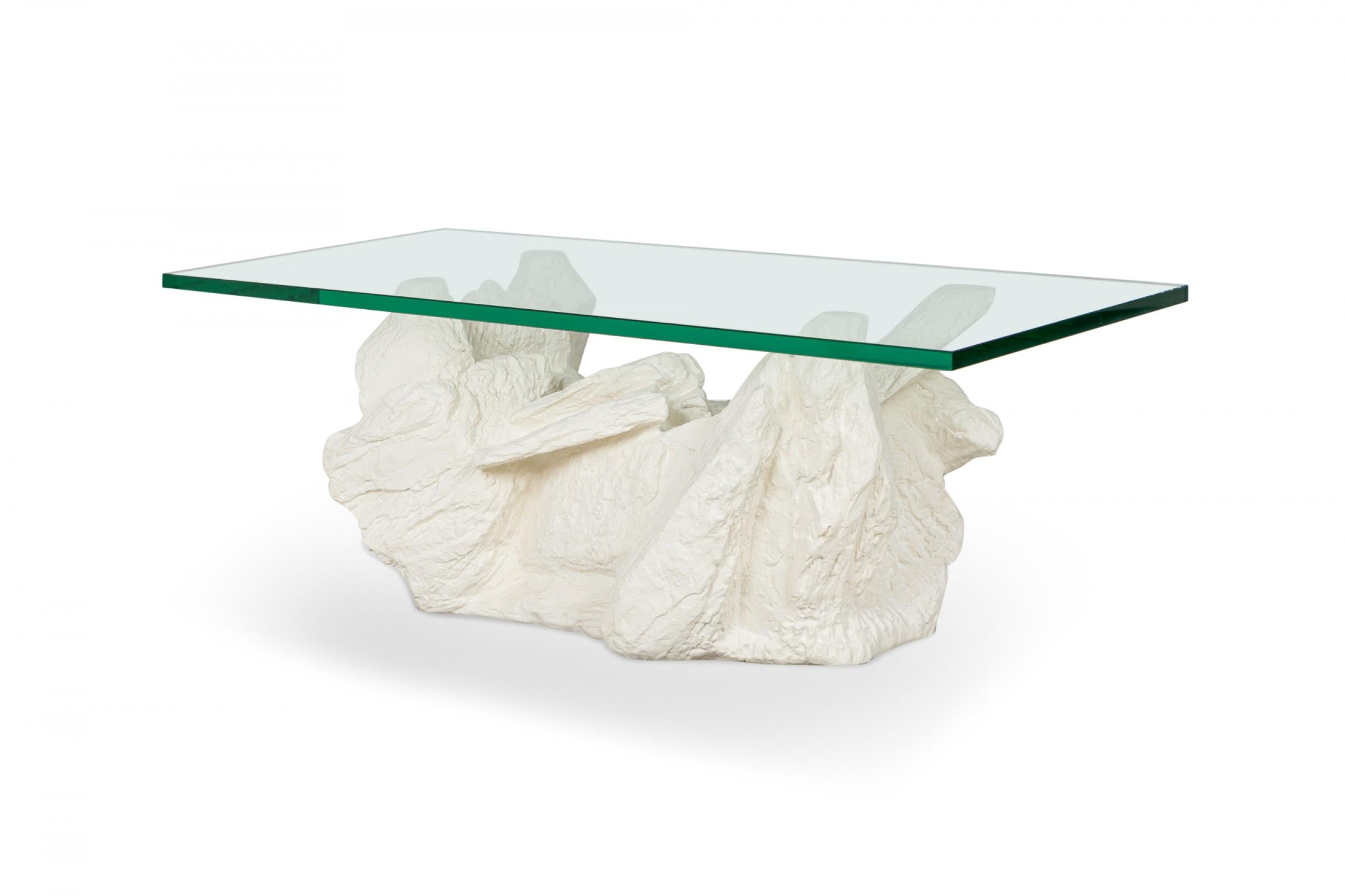 American Mid-Century cocktail / coffee table with a rectangular glass top supported by a white plaster faux bois stone base. (SIRMOS)

