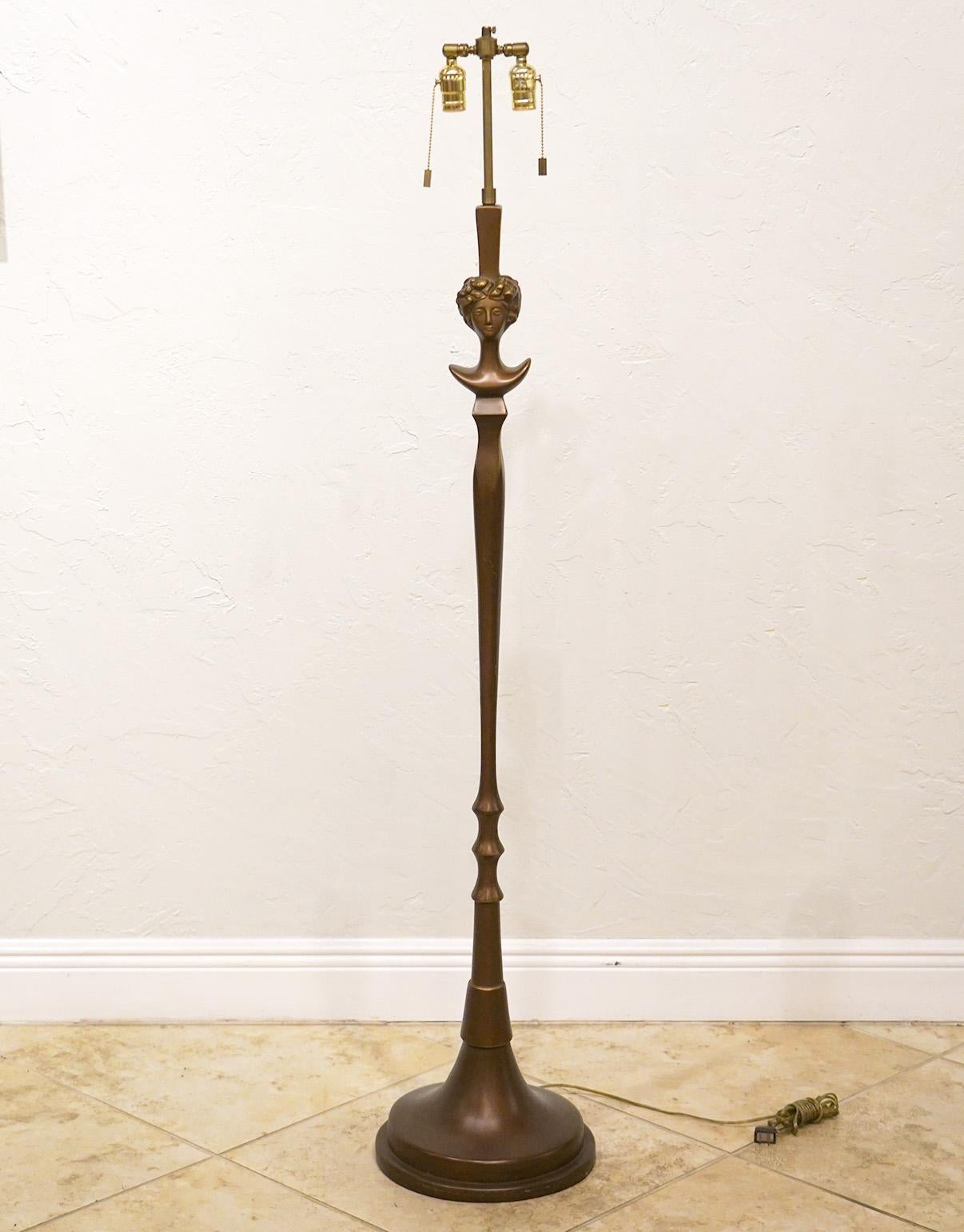 This artistic floor lamp by Sirmos, Long Island City, features a replica of Giacometti's sculpture lamp 'Tete de Femme'. Retaining its original Sirmos label it dates to around 1970 and is made of composite with a bronze style finish.