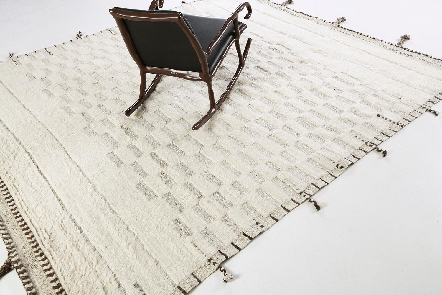 Sirocco' is a stunning handwoven ivory rug with embossed detailing in a checkered pattern atop a natural gray pile weave. Beautiful tassels and bordered designs add a timely and one-of-a-kind essence for the modern design world. Haute Bohemian
