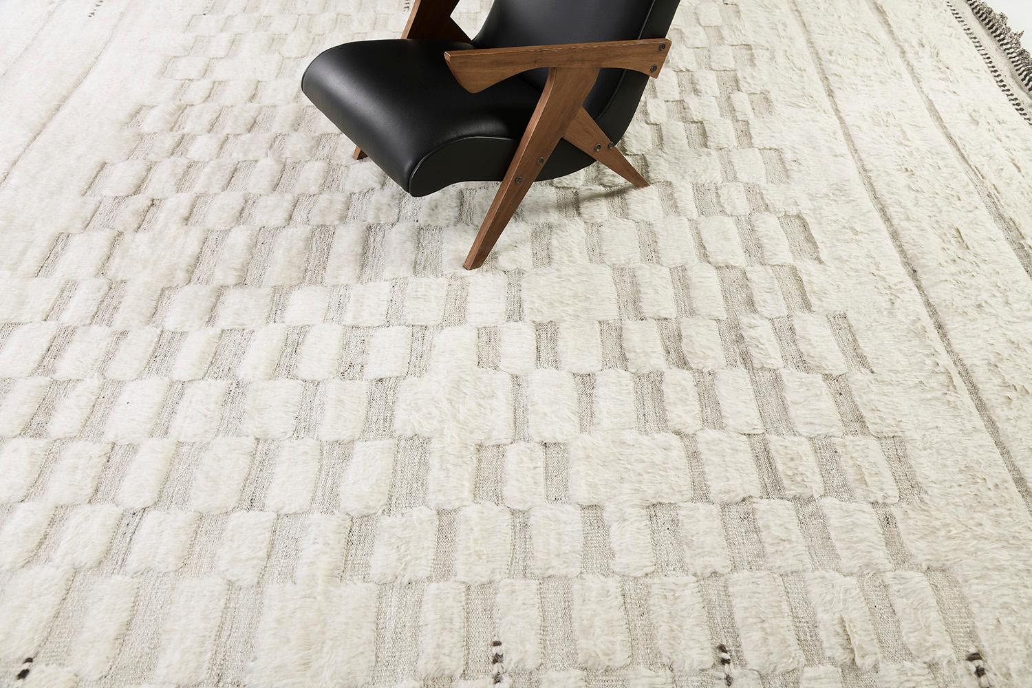 Sirocco' is a stunning handwoven ivory rug with embossed detailing in a checkered pattern atop a natural gray pile weave. Beautiful tassels and bordered designs add a timely and one-of-a-kind essence for the modern design world. Haute Bohemian