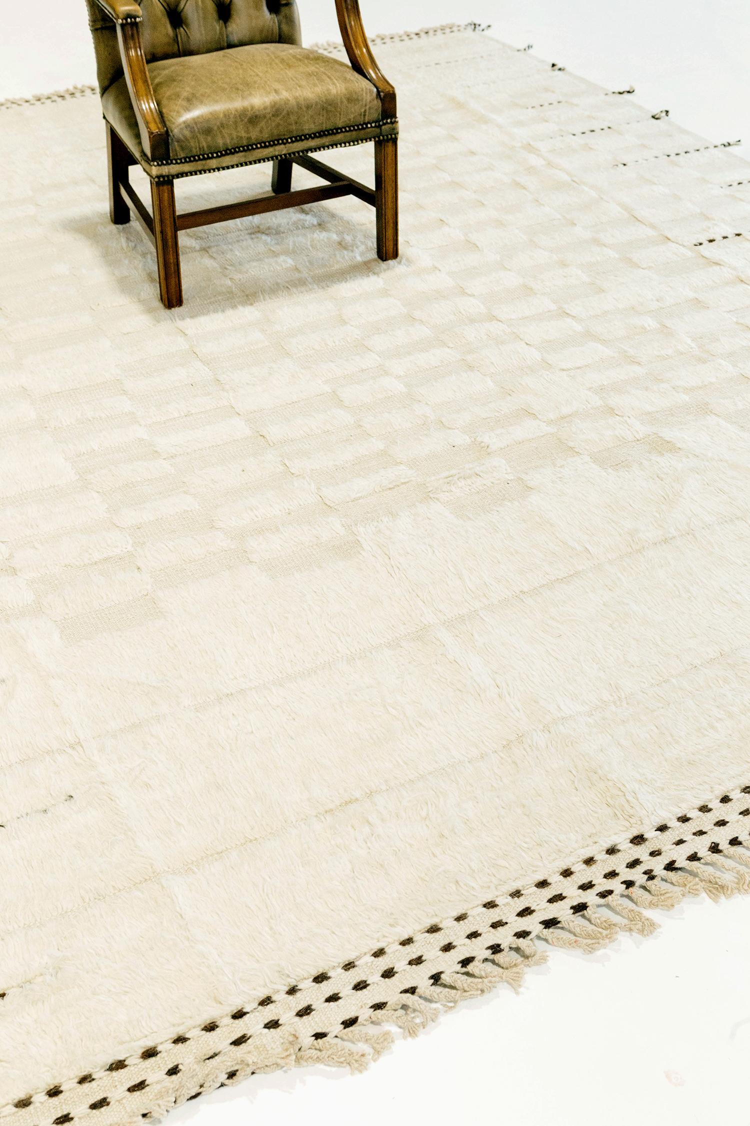 Sirocco' is a stunning handwoven white rug with embossed detailing in a checkered pattern atop a ivory pile weave. Beautiful tassels and bordered designs add a timely and one of a kind essence for the modern design world. Haute Bohemian Collection: