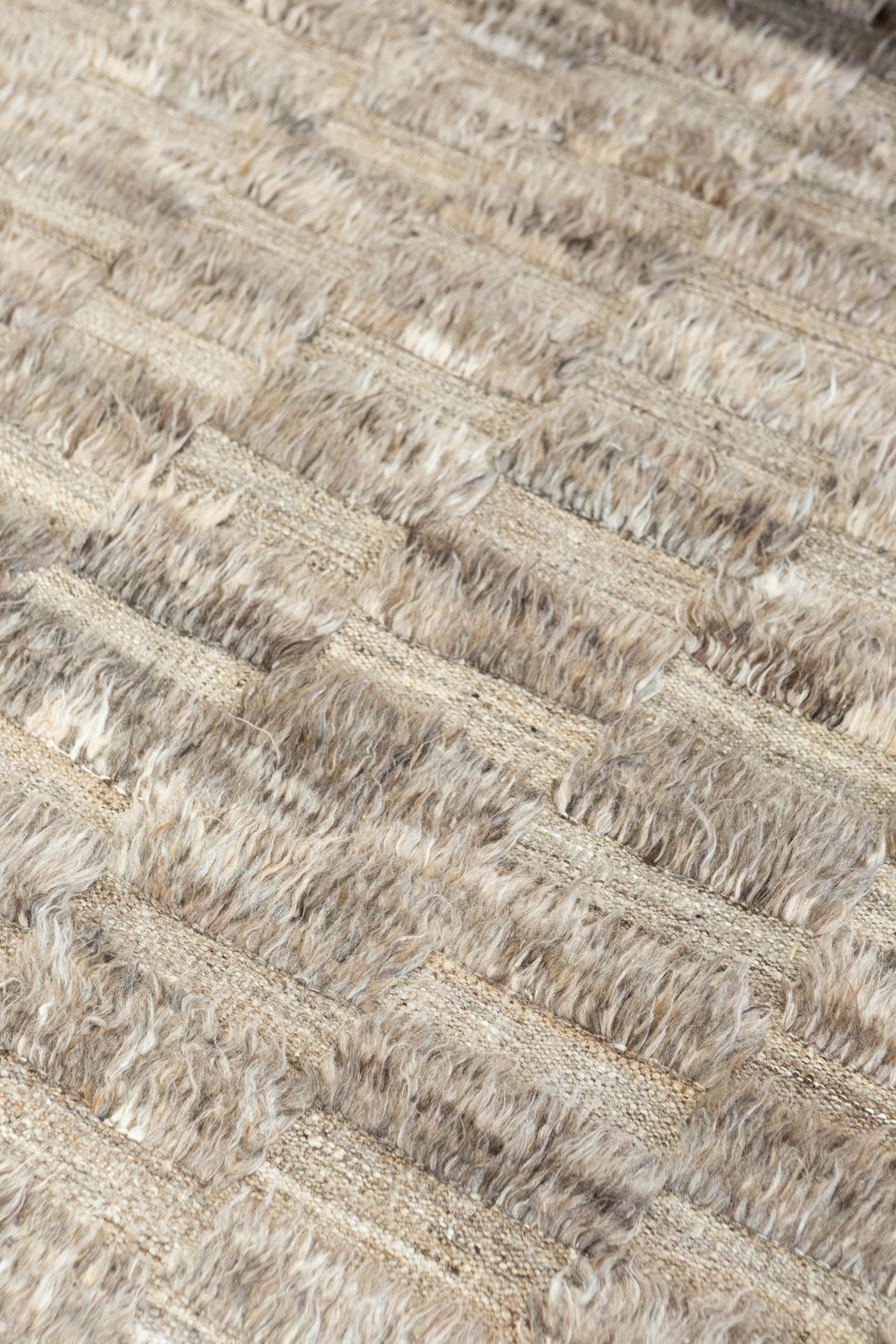 Sirocco' is a stunning handwoven fog colored rug with embossed detailing in a checkered pattern atop a pile weave. Beautiful tassels and bordered designs add a timely and one of a kind essence for the modern design world. Haute Bohemian collection: