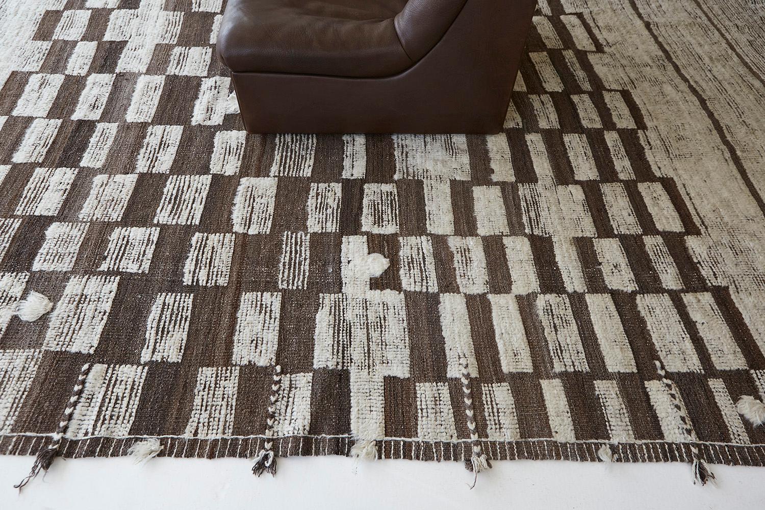 Sirocco' is a stunning hand-woven ivory rug with embossed detailing in a checkered pattern atop a natural gray pile weave. Beautiful tassels and bordered designs add a timely and one-of-a-kind essence for the modern design world. Haute Bohemian