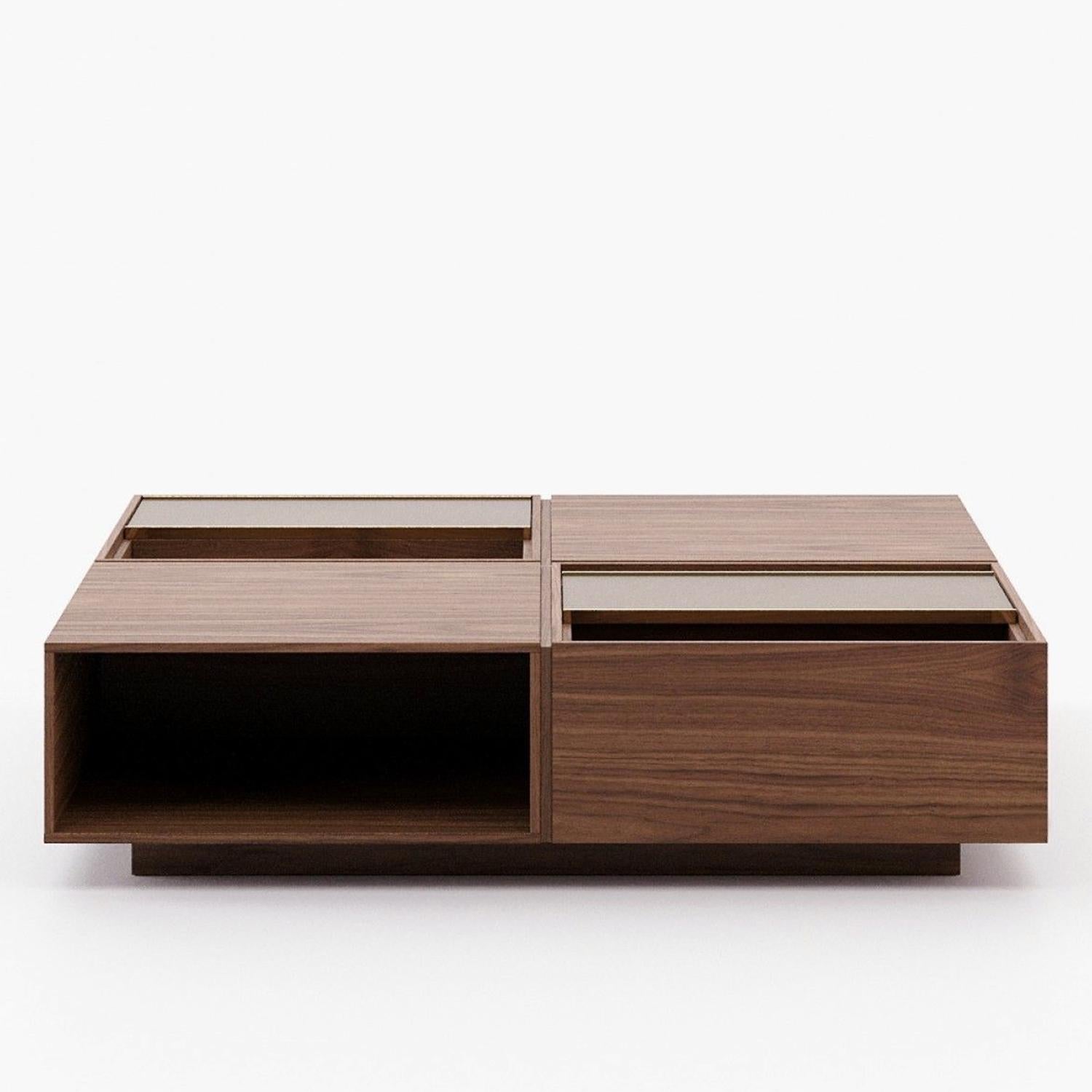 Table basse Structure en bois Sisla, finition plaquée noyer,
avec 2 plateaux coulissants en cuir en finition grise. Avec acier inoxydable 
détails en finition dorée polie.
Egalement disponible sur demande avec d'autres finitions en bois, cuir et