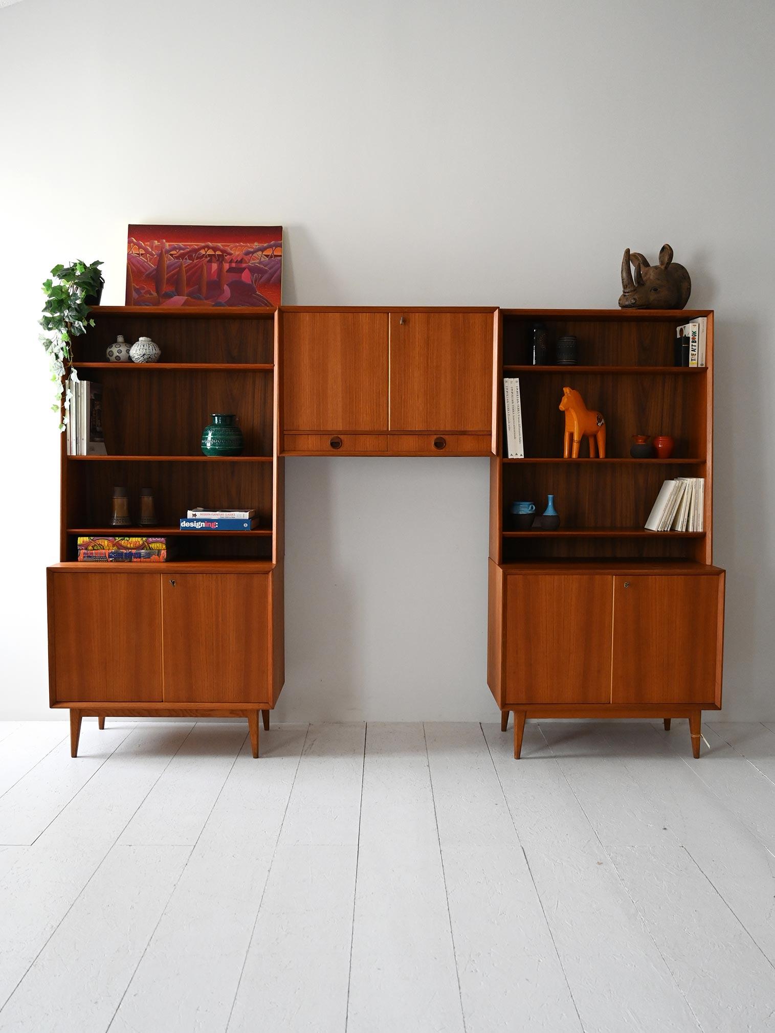 Sistema di librerie vintage con ante a battente in teak e modulo contenitore sospeso con ante e cassetti integrati.

Sistema di arredo modulare scandinavo originale degli anni 60, composto da due librerie in teak con struttura inclinata, ripiani a