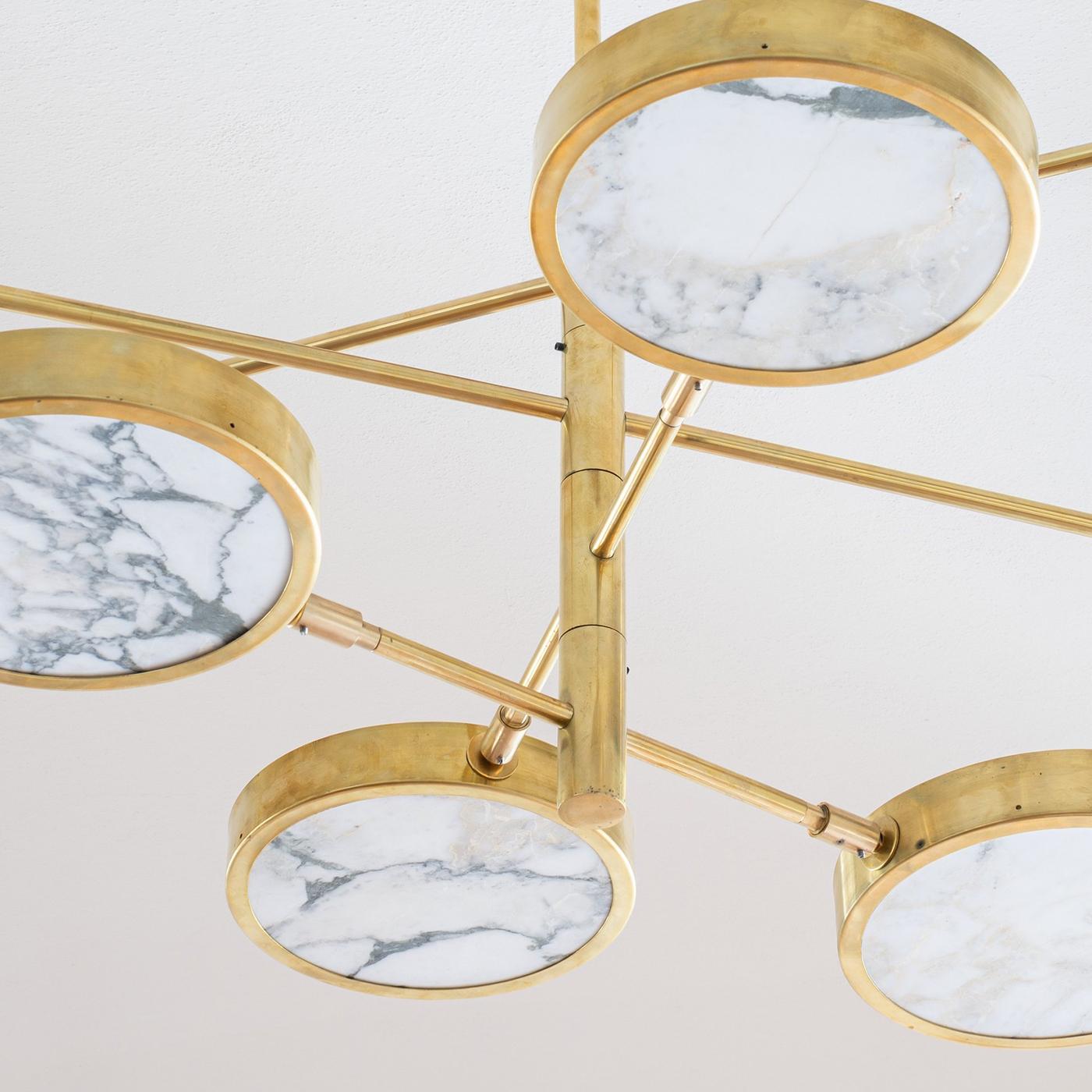 An orbital structure allowing for endless configurations defines this precious golden chandelier. The warm tone of its eight-light structure is splendidly matched by the golden veins of the thin Calacatta Oro marble disks, which release a sublime