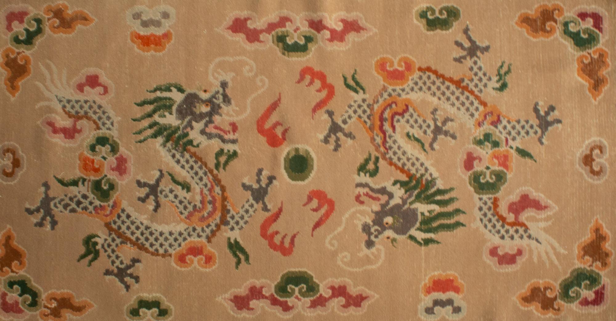 Sitting and sleeping Tibetan double dragon Khaden rug, circa 1970s, warm beige ground weave with two colorful dragons, symbols are benevolent creatures, protectors of Buddhism and full of creative energy, chasing the Flaming Pearl (in the middle), a
